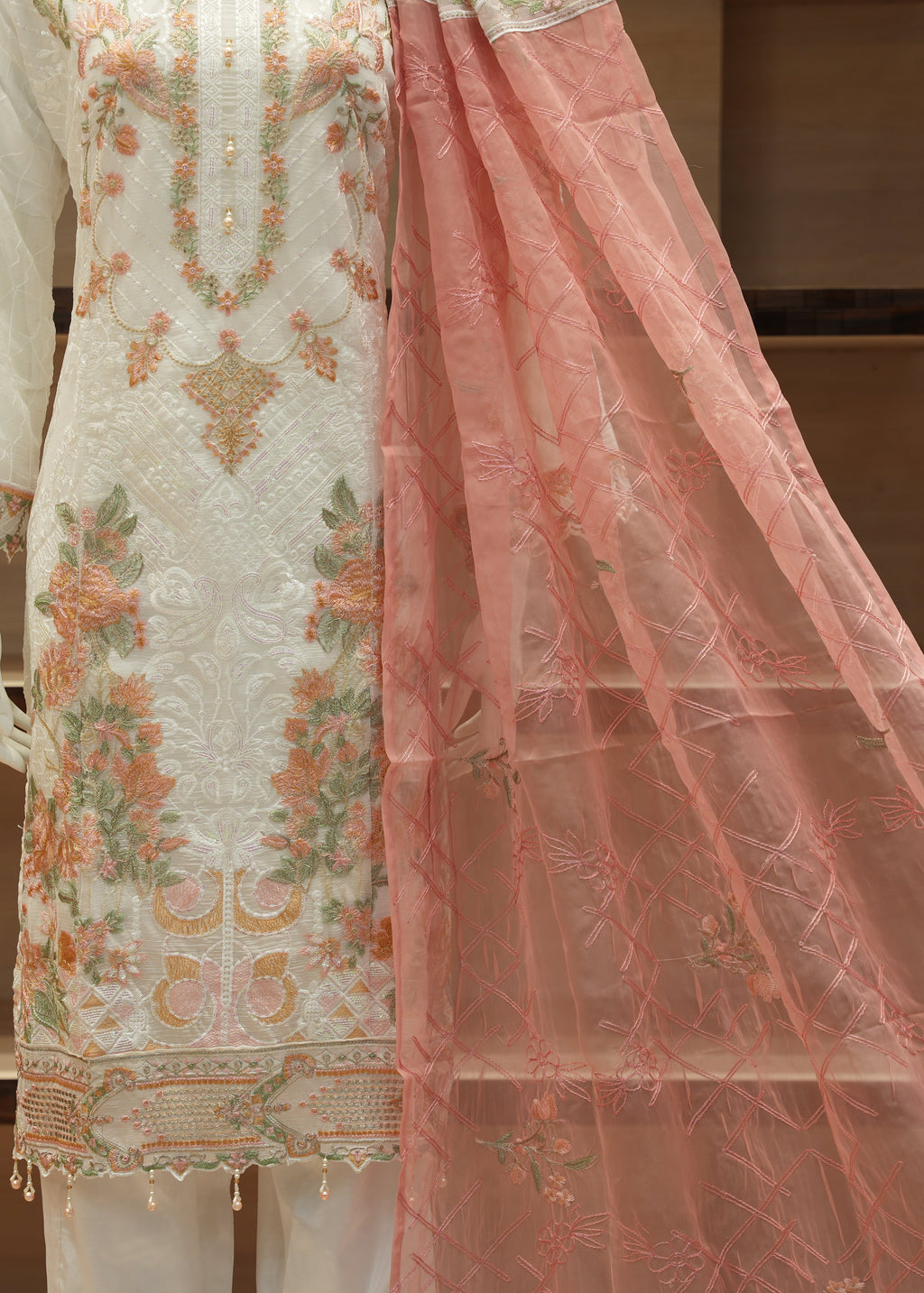 Embroidered traditional outfit with a pink dupatta on a neutral background