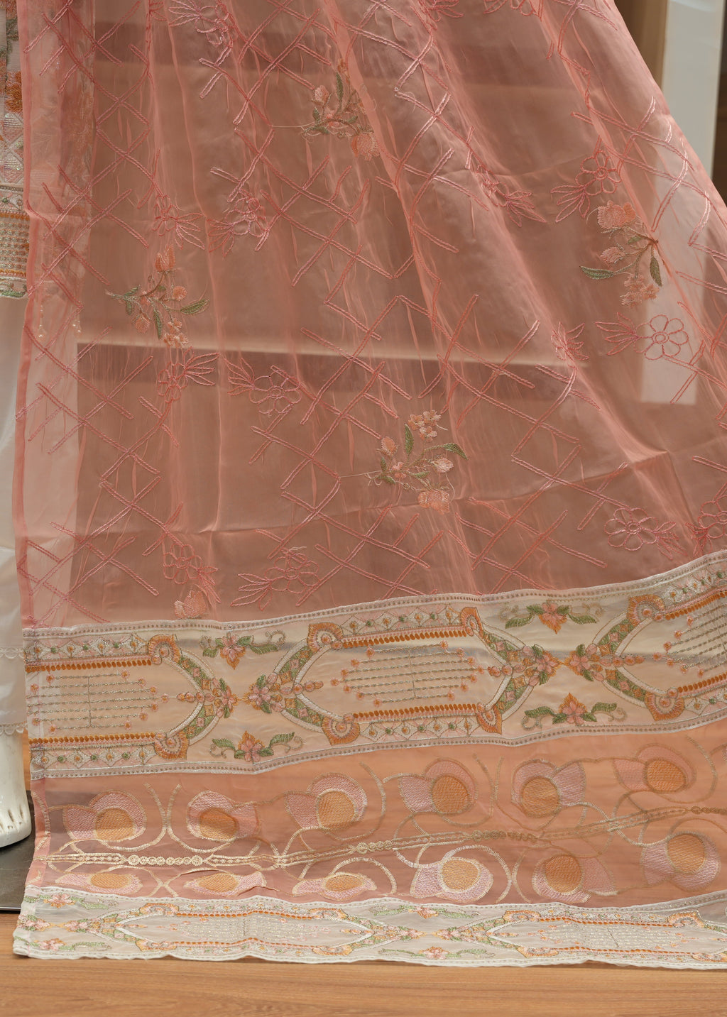 Decorative pink fabric with intricate patterns on a wooden floor.