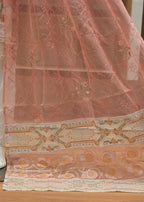 Decorative pink fabric with intricate patterns on a wooden floor.