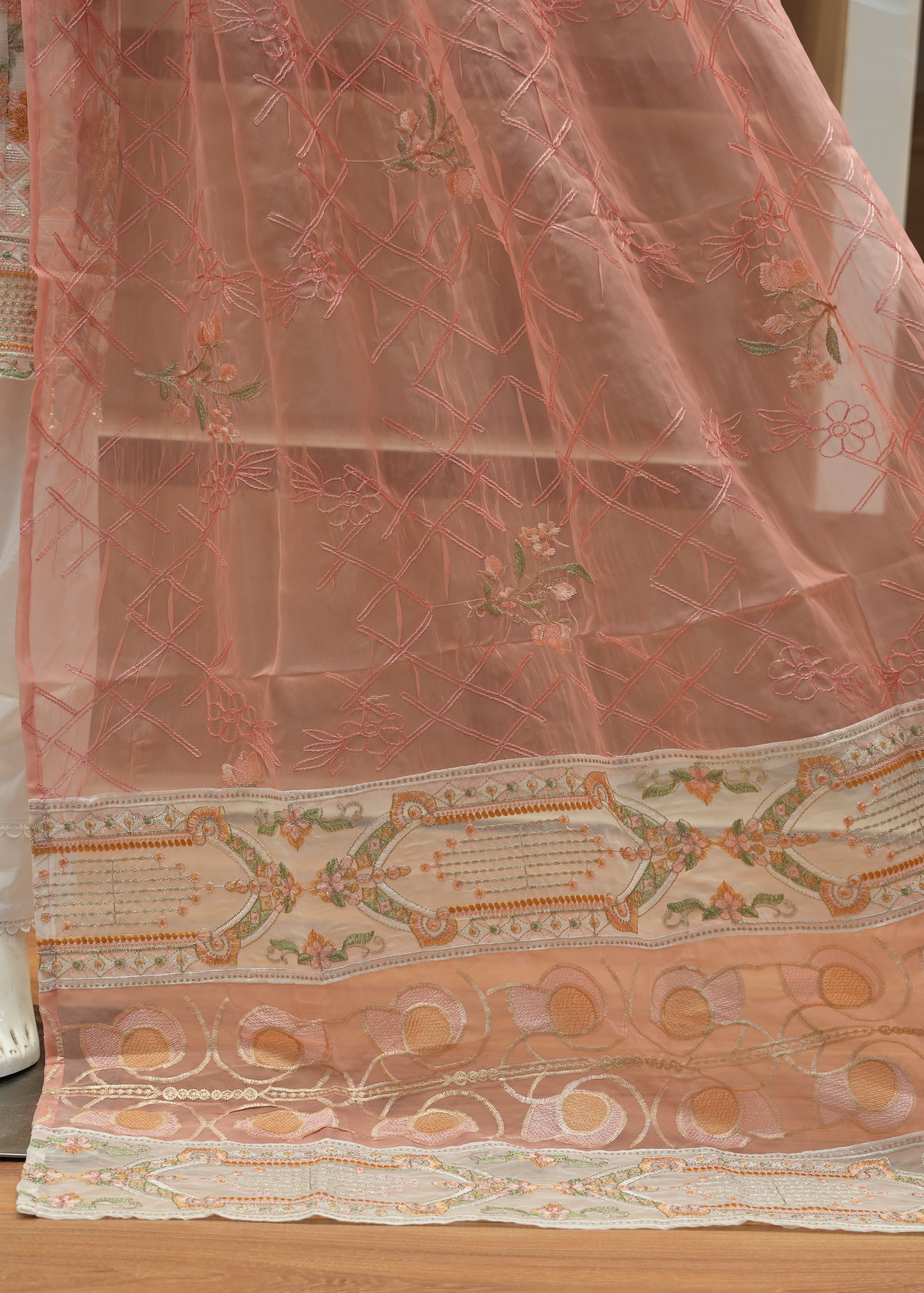 Decorative pink fabric with intricate patterns on a wooden floor.