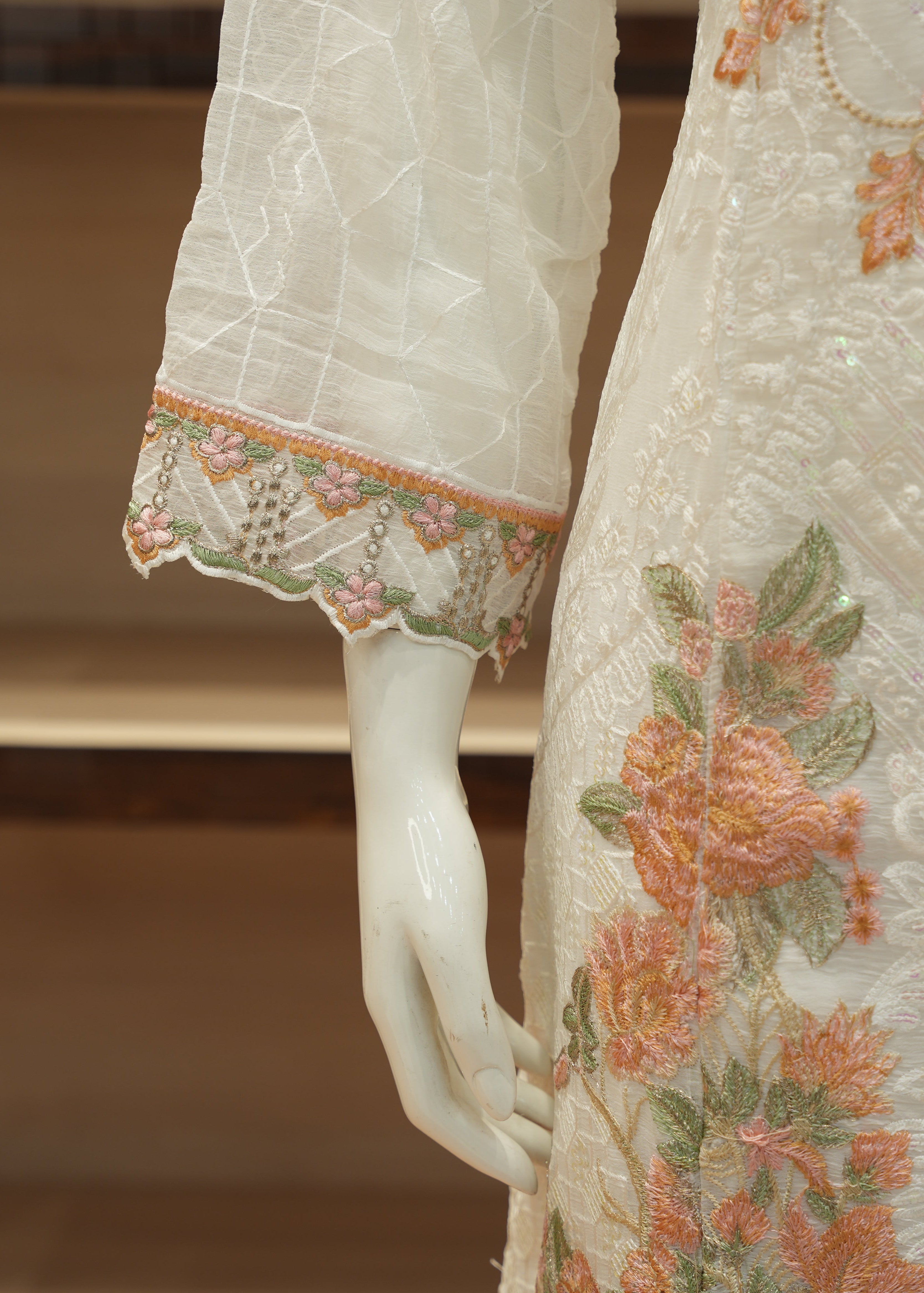 Close-up of a white embroidered garment with floral patterns on a mannequin.