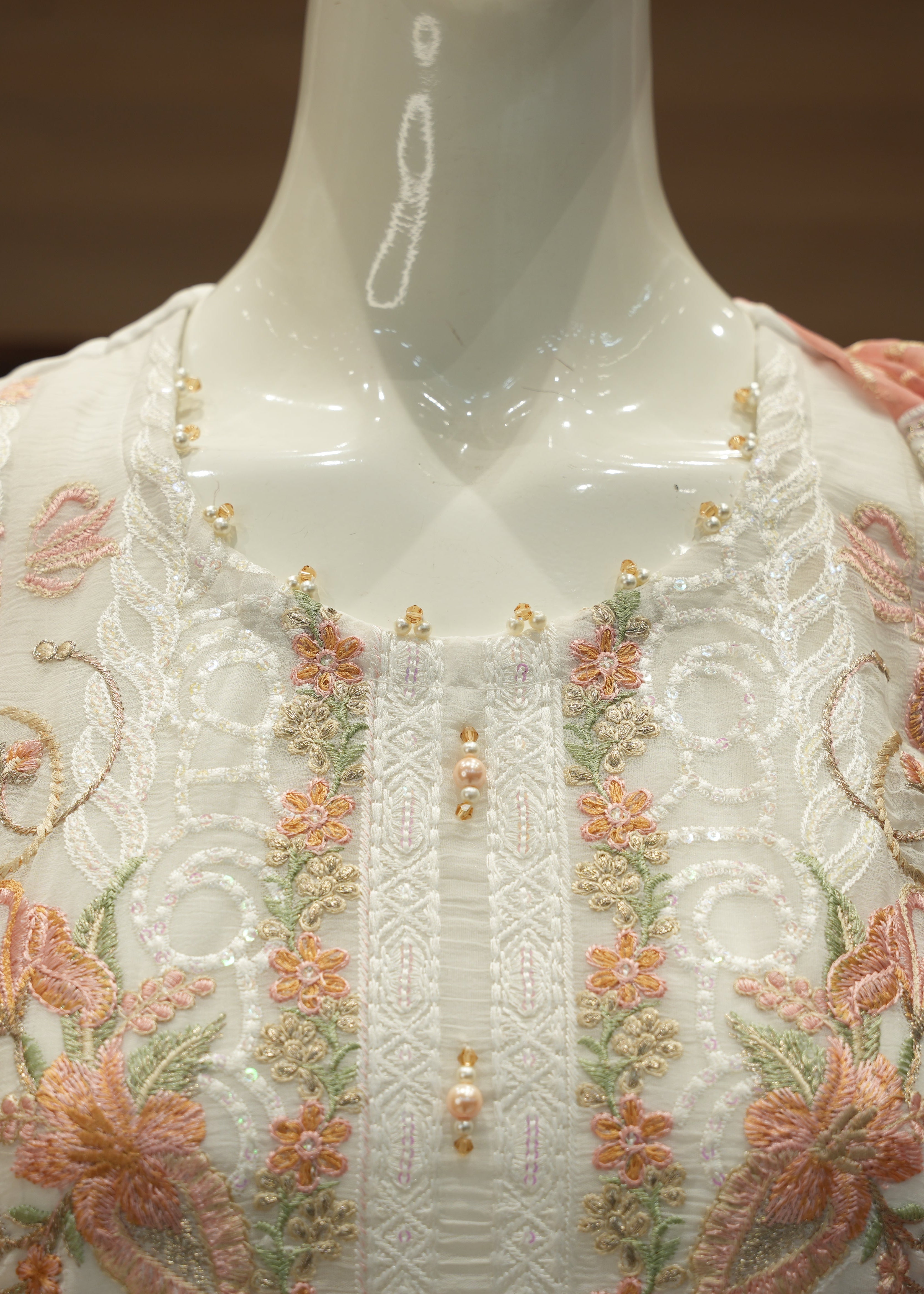 White embroidered garment on a mannequin with floral patterns