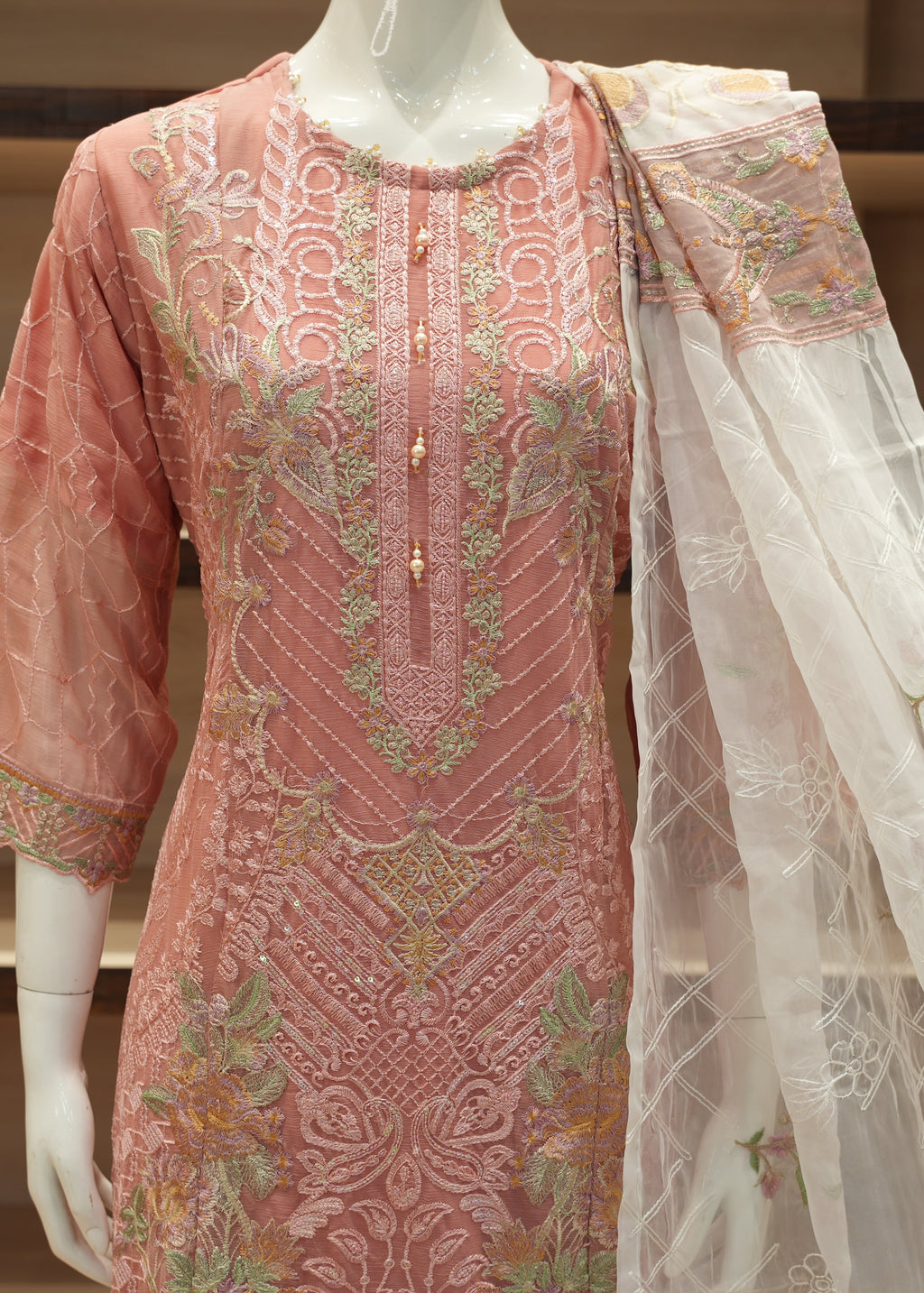 Pink embroidered traditional outfit with a white dupatta on a mannequin against a neutral background