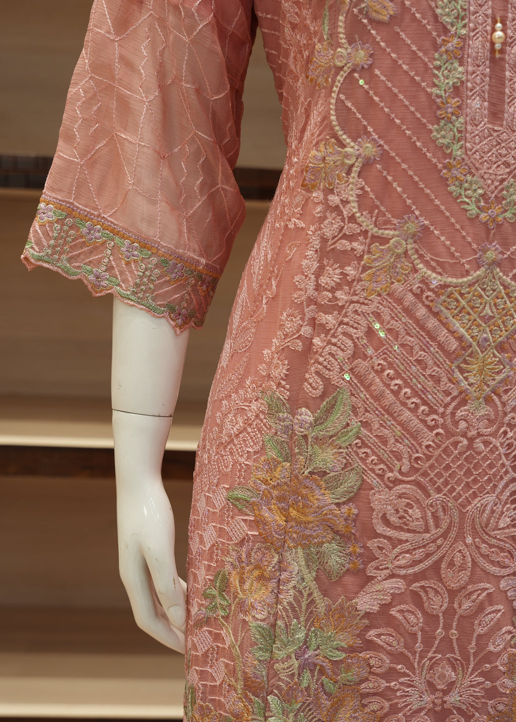 Mannequin wearing a pink embroidered dress with intricate patterns.