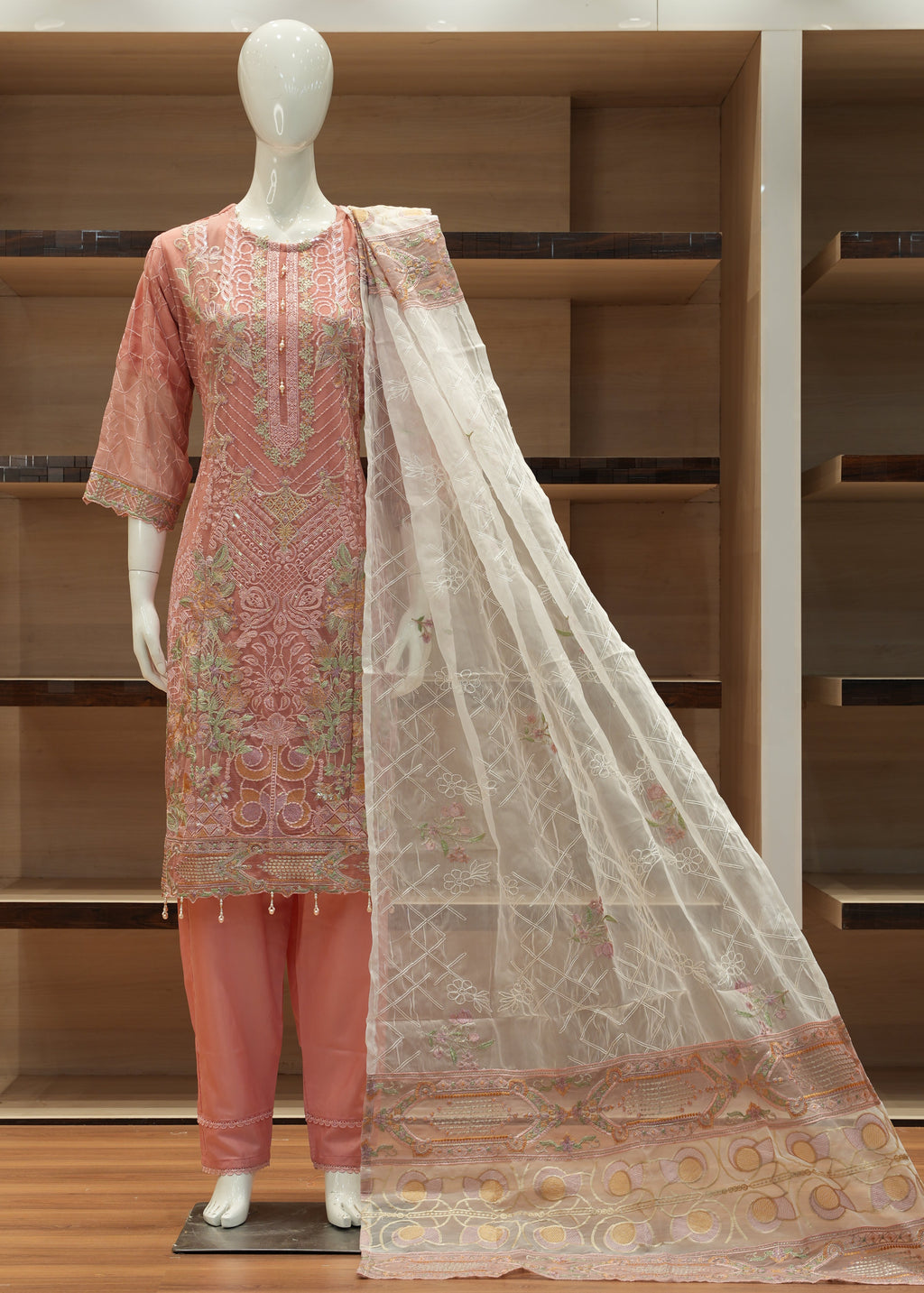 Decorative pink and beige scarf draped over a wooden shelf with a mirror.