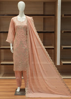 Mannequin wearing a pink dress with lace details against a wooden background