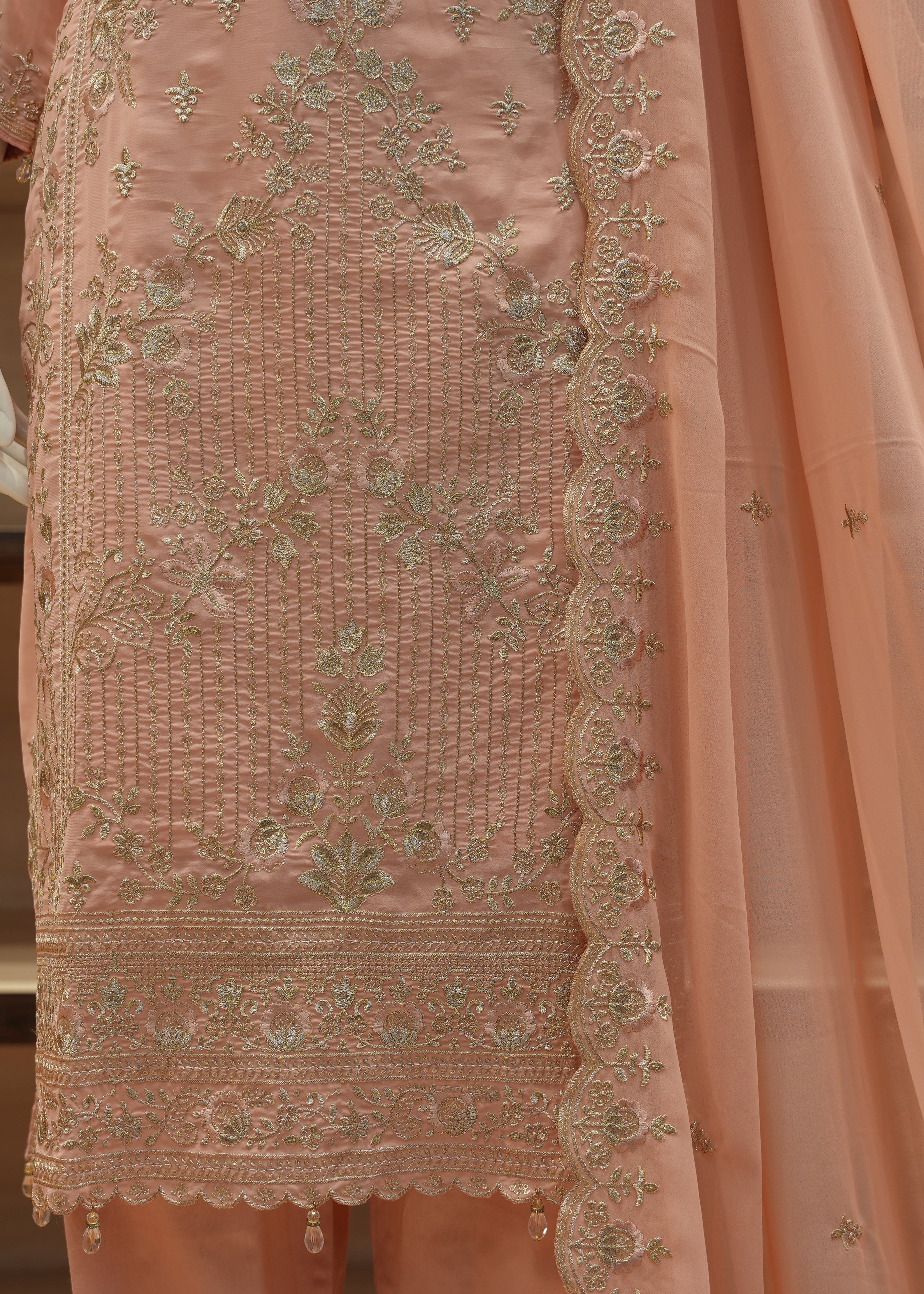 Peach-colored embroidered traditional outfit with a sheer dupatta.