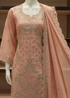 Peach-colored embroidered traditional outfit on a mannequin with a plain background
