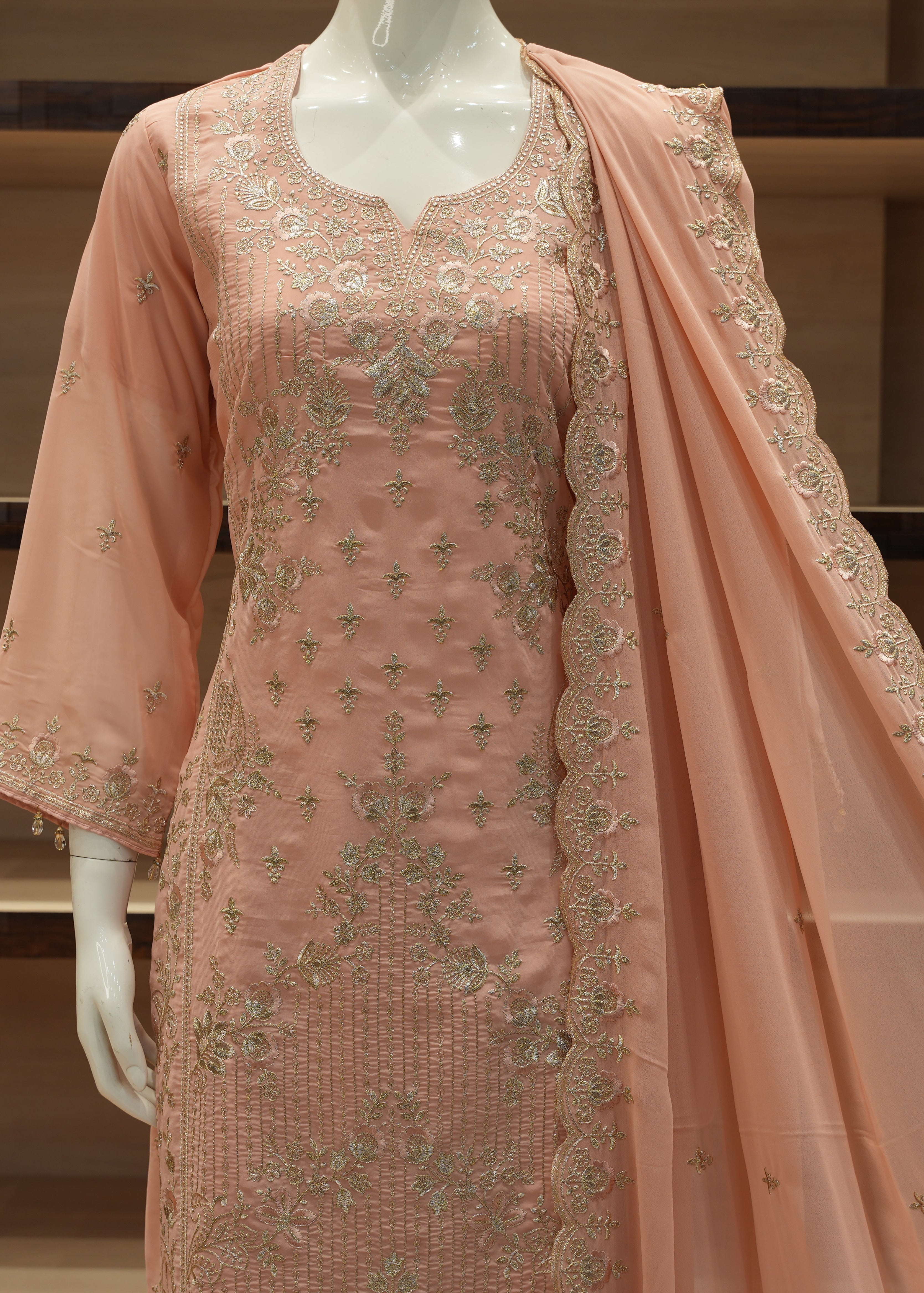 Peach-colored embroidered traditional outfit on a mannequin with a plain background