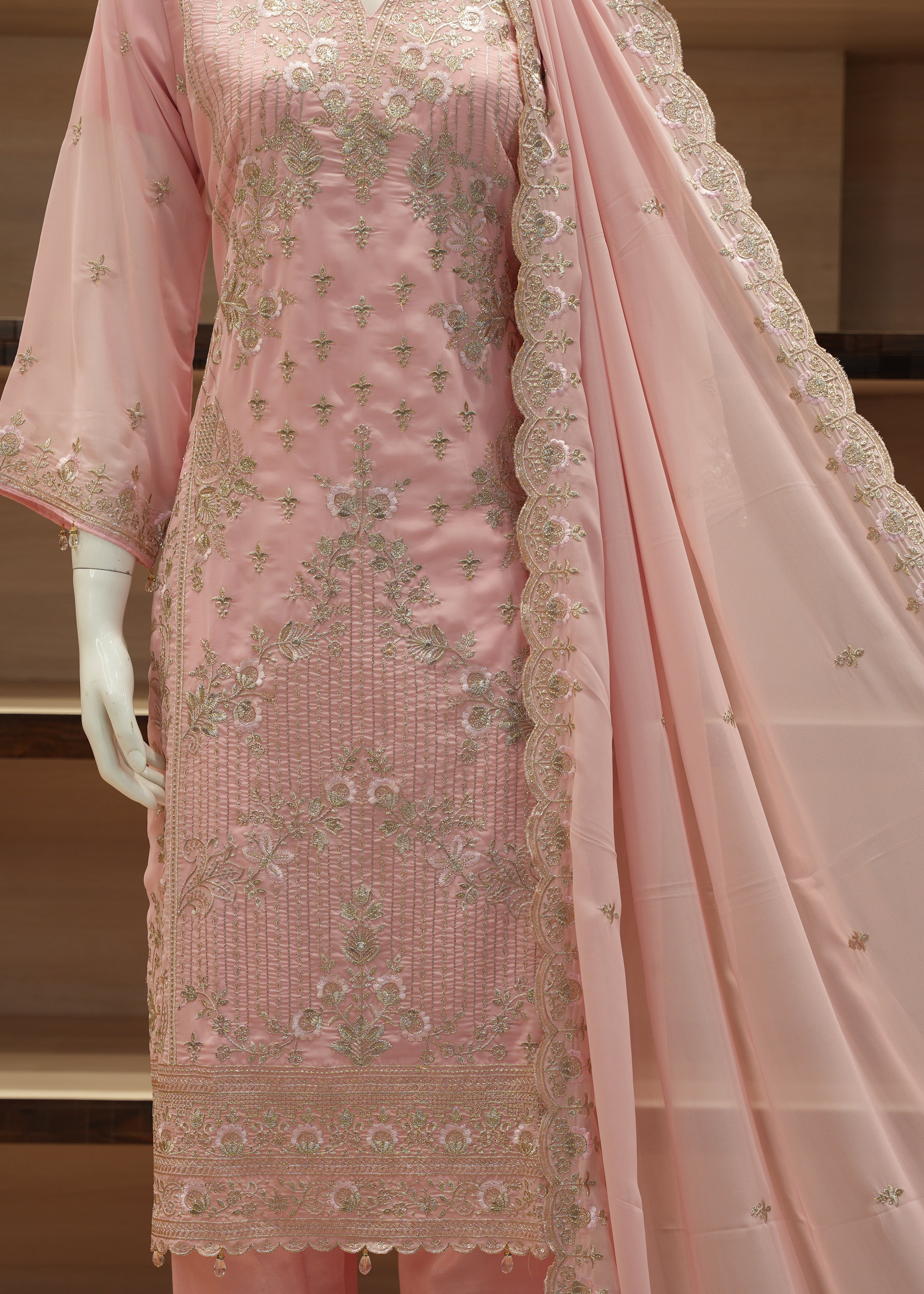 Pink embroidered traditional outfit with a dupatta on a mannequin against a neutral background