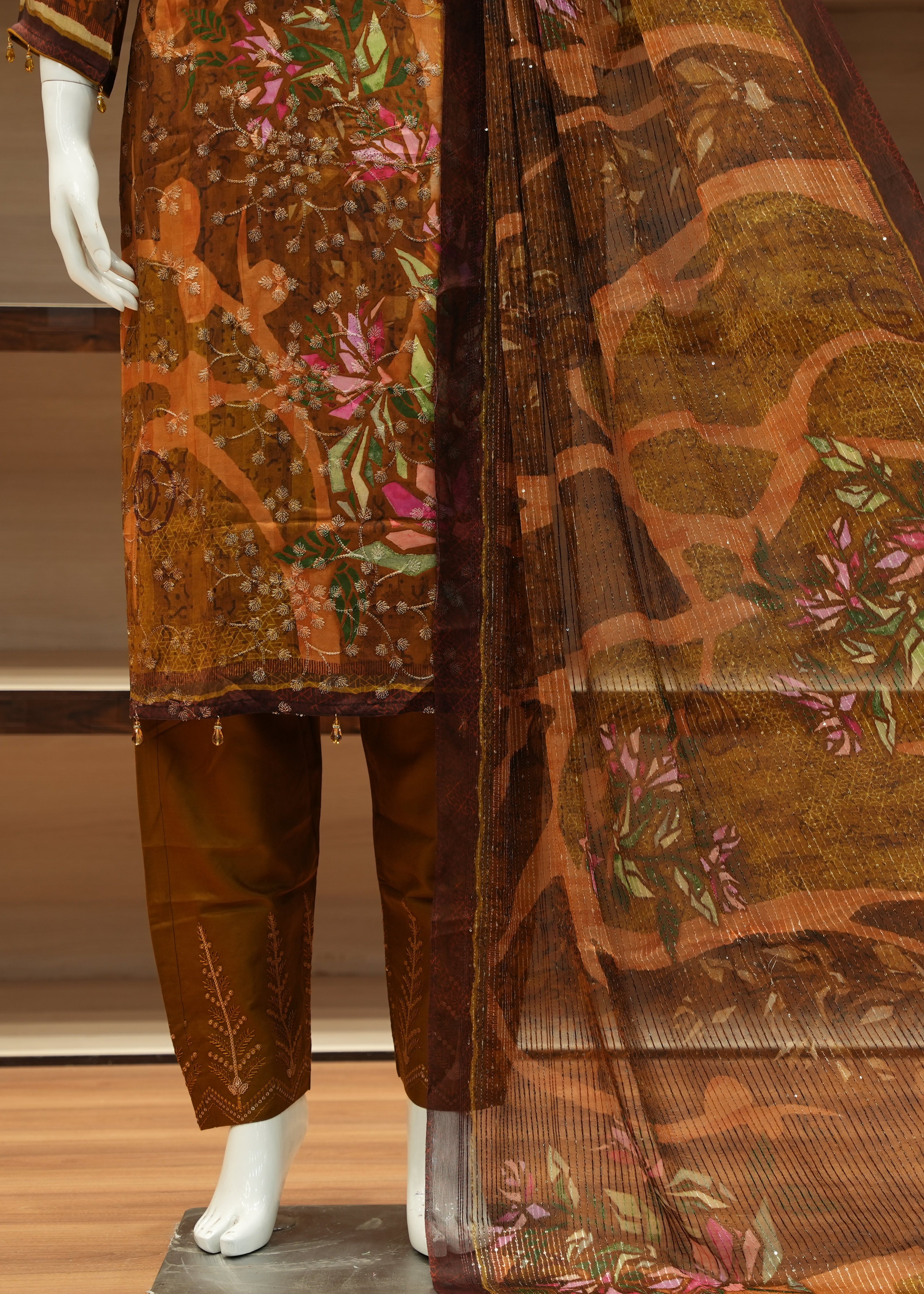 Mannequin wearing a traditional outfit with floral patterns on a wooden floor.