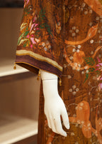 Mannequin hand wearing a brown embroidered garment with floral patterns on a neutral background