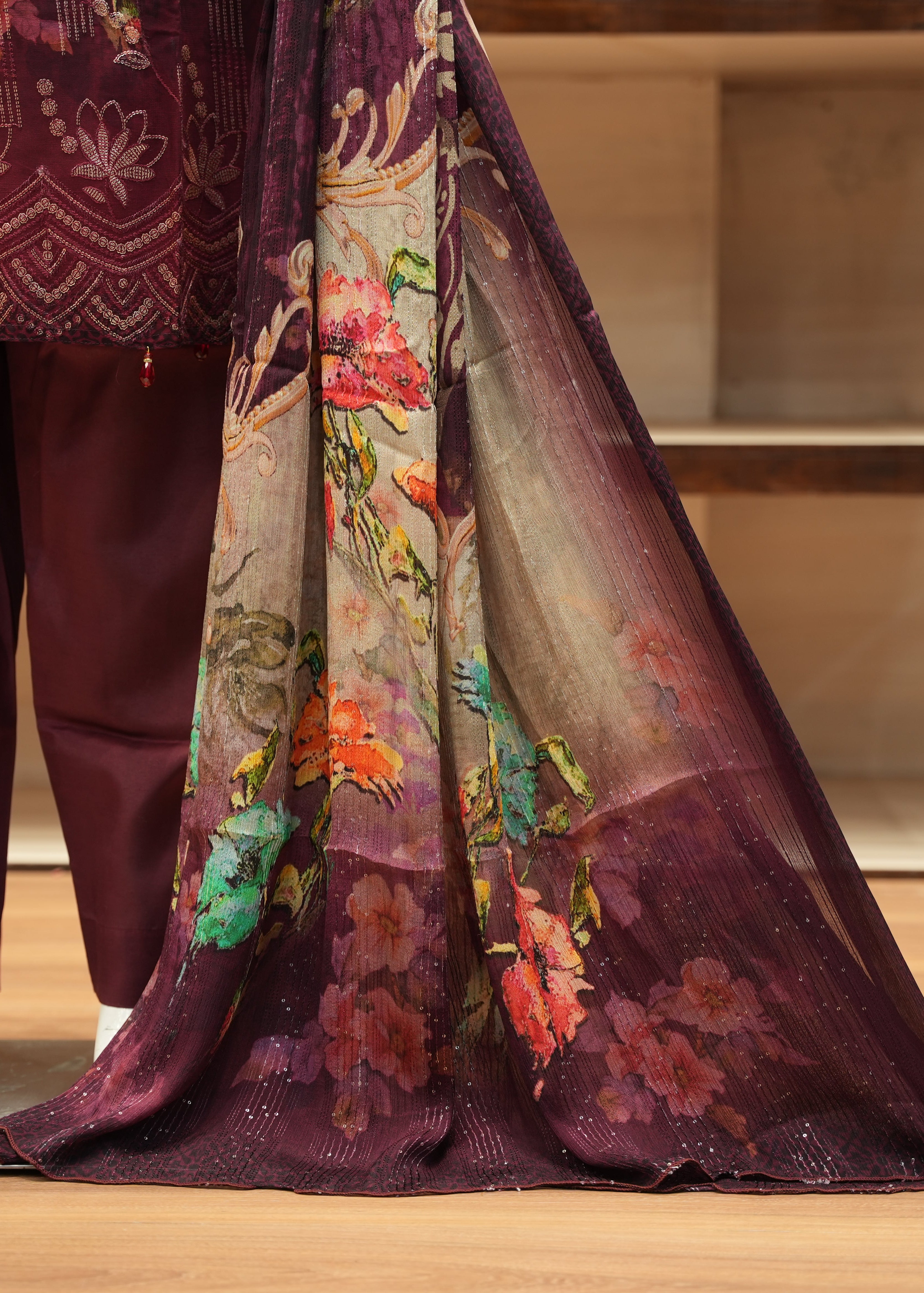 Traditional outfit with a floral-patterned fabric draped over a person, set against a neutral background.