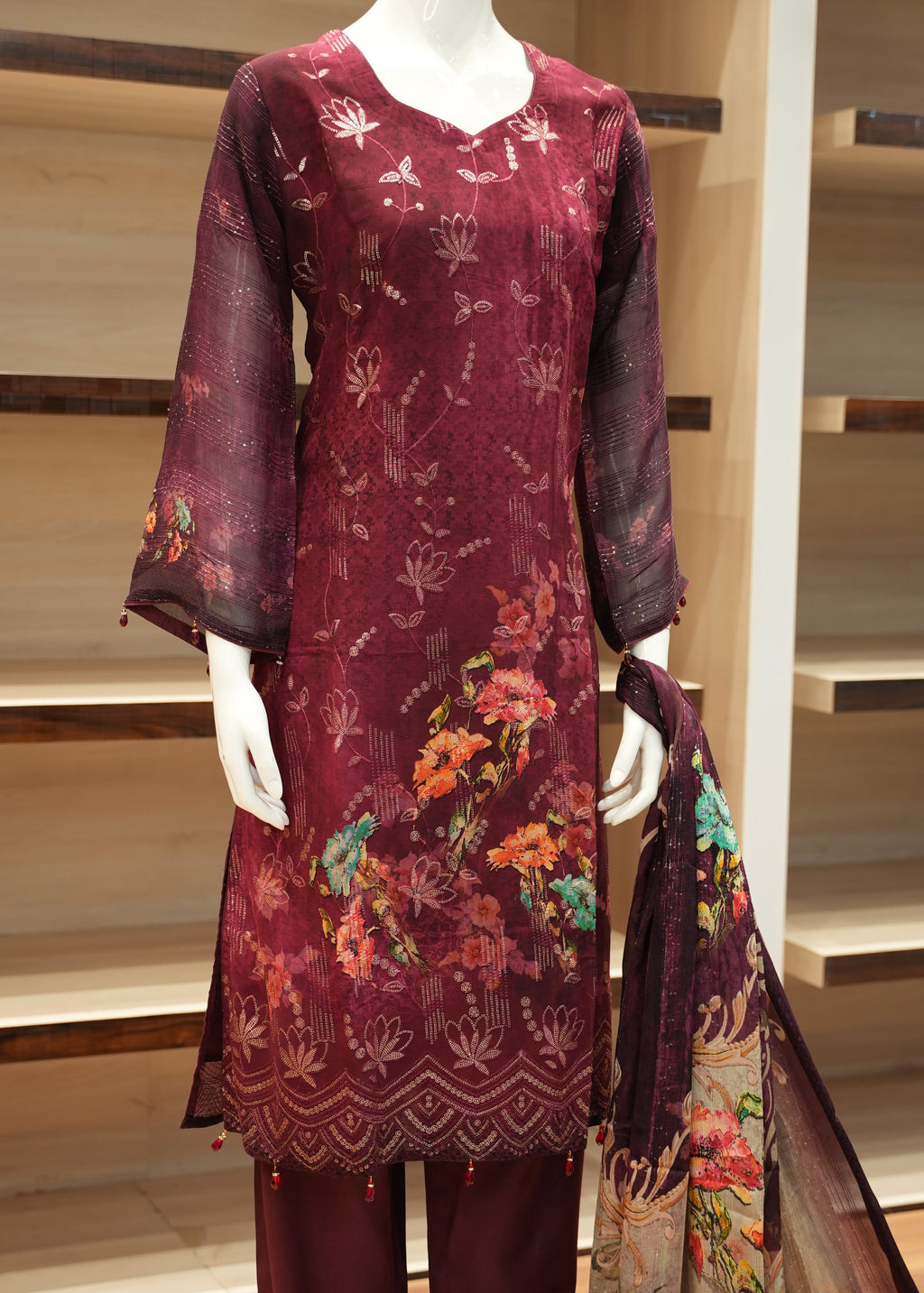 Maroon fabric with floral patterns displayed on a wooden frame.