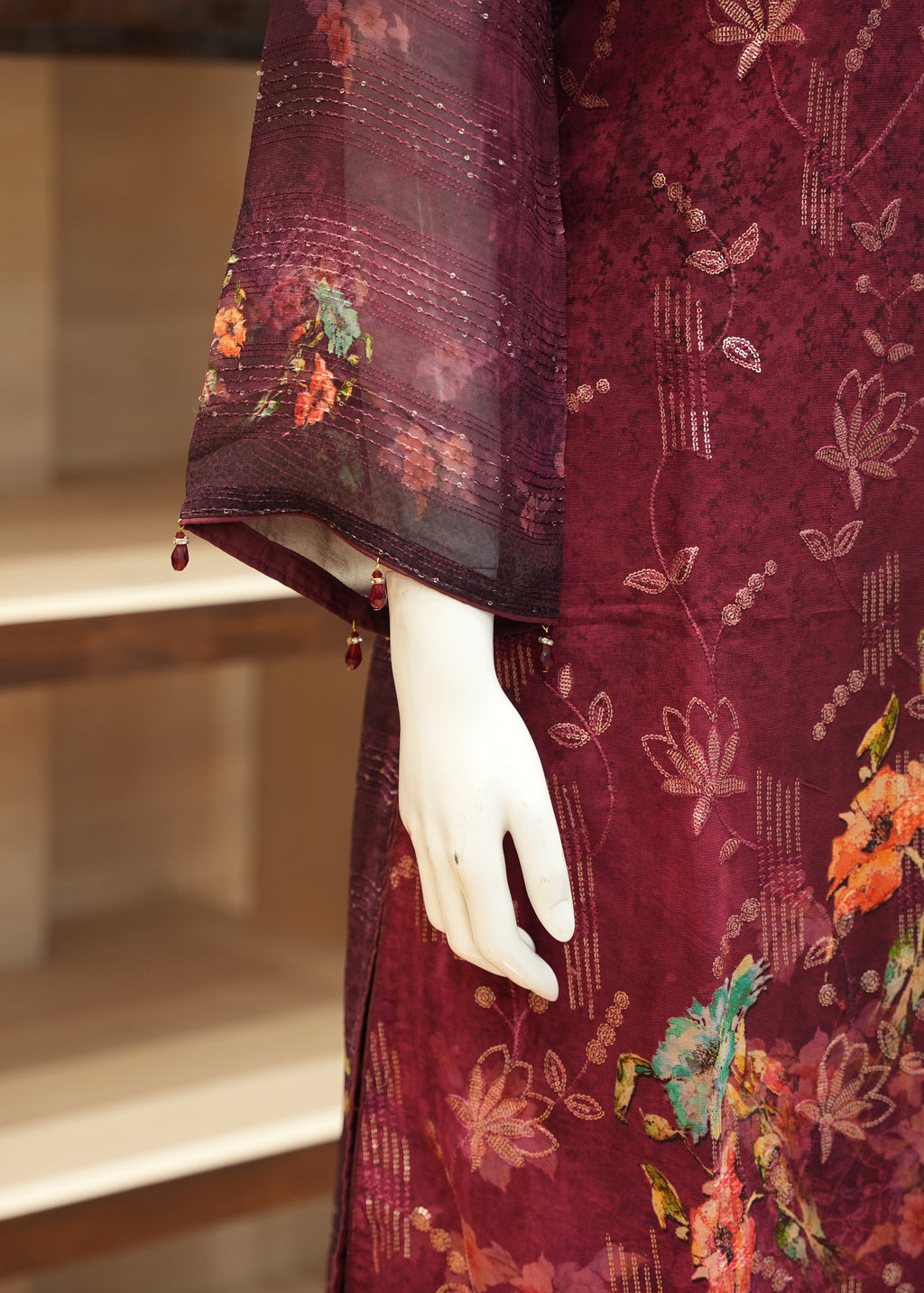 Maroon garment with floral patterns on a mannequin against a neutral background
