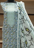 Light blue fabric with floral patterns draped over a mannequin against a wooden shelf background