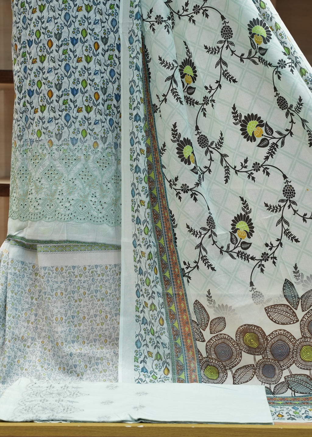 Two pieces of fabric with floral patterns on a wooden surface.