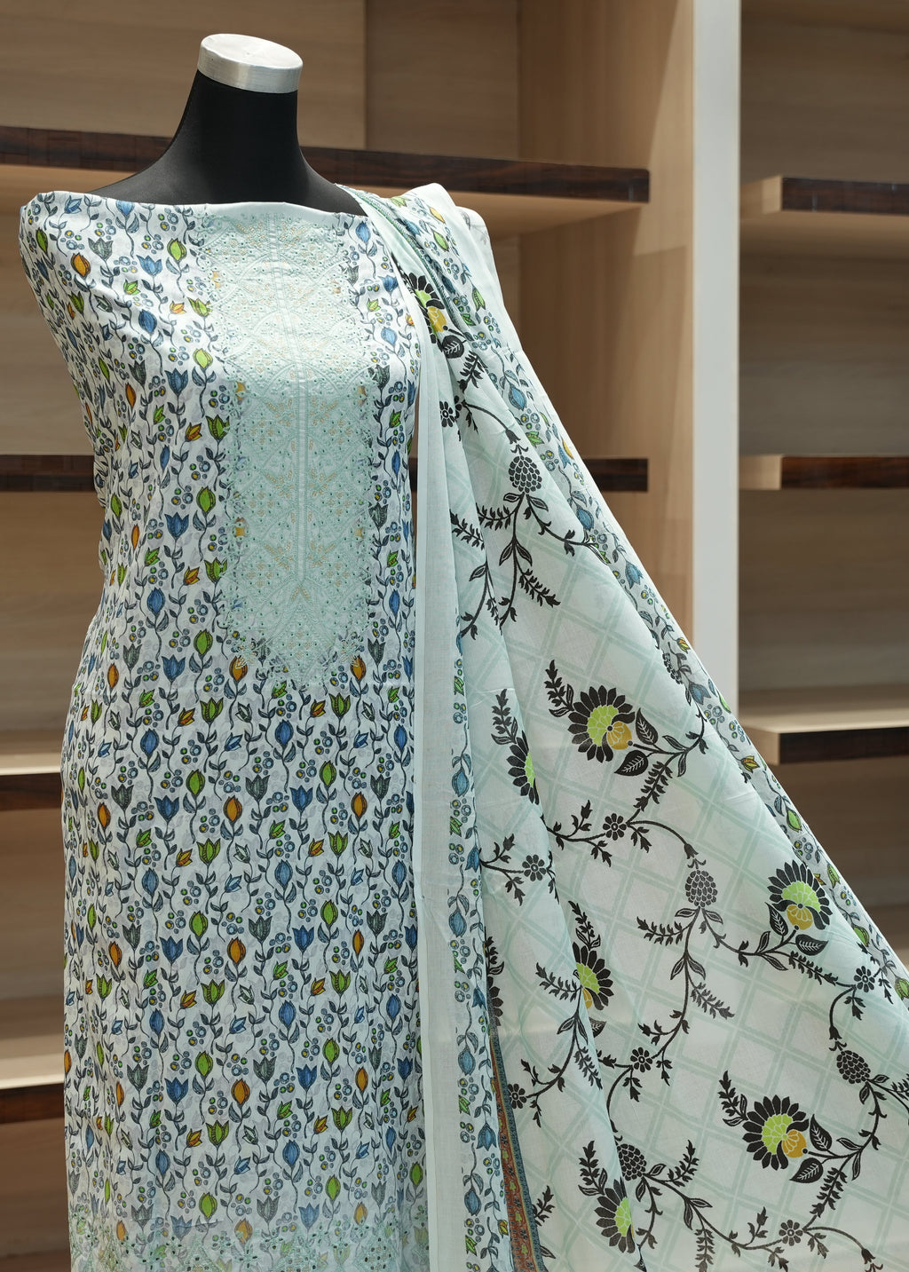Mannequin wearing a light blue floral dress with a wooden shelf background