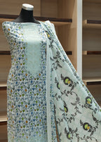 Mannequin wearing a light blue floral dress with a wooden shelf background