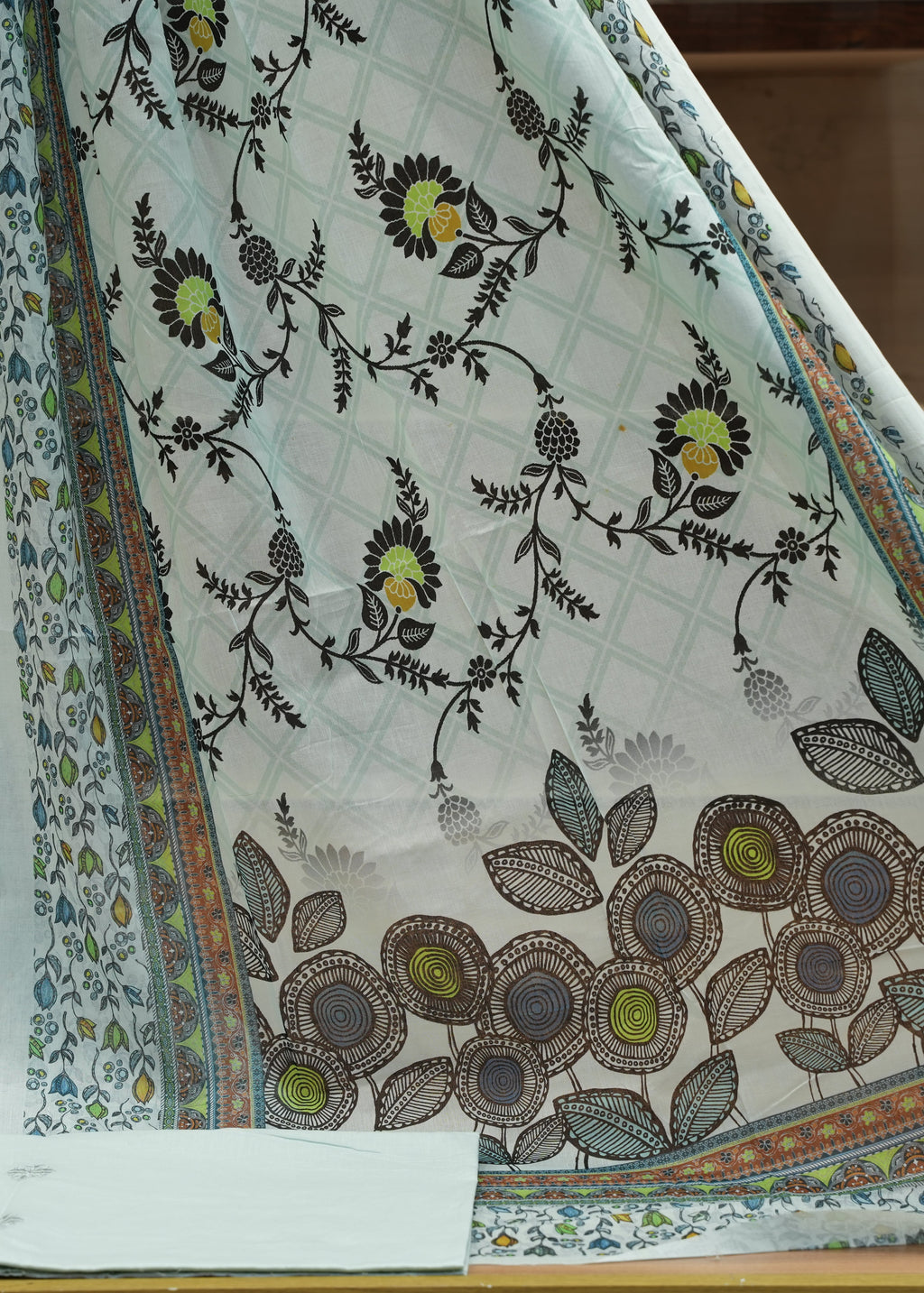 Floral patterned fabric with a colorful border on a wooden surface