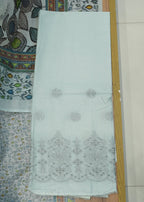 White fabric with intricate black patterns on a wooden surface with a patterned background