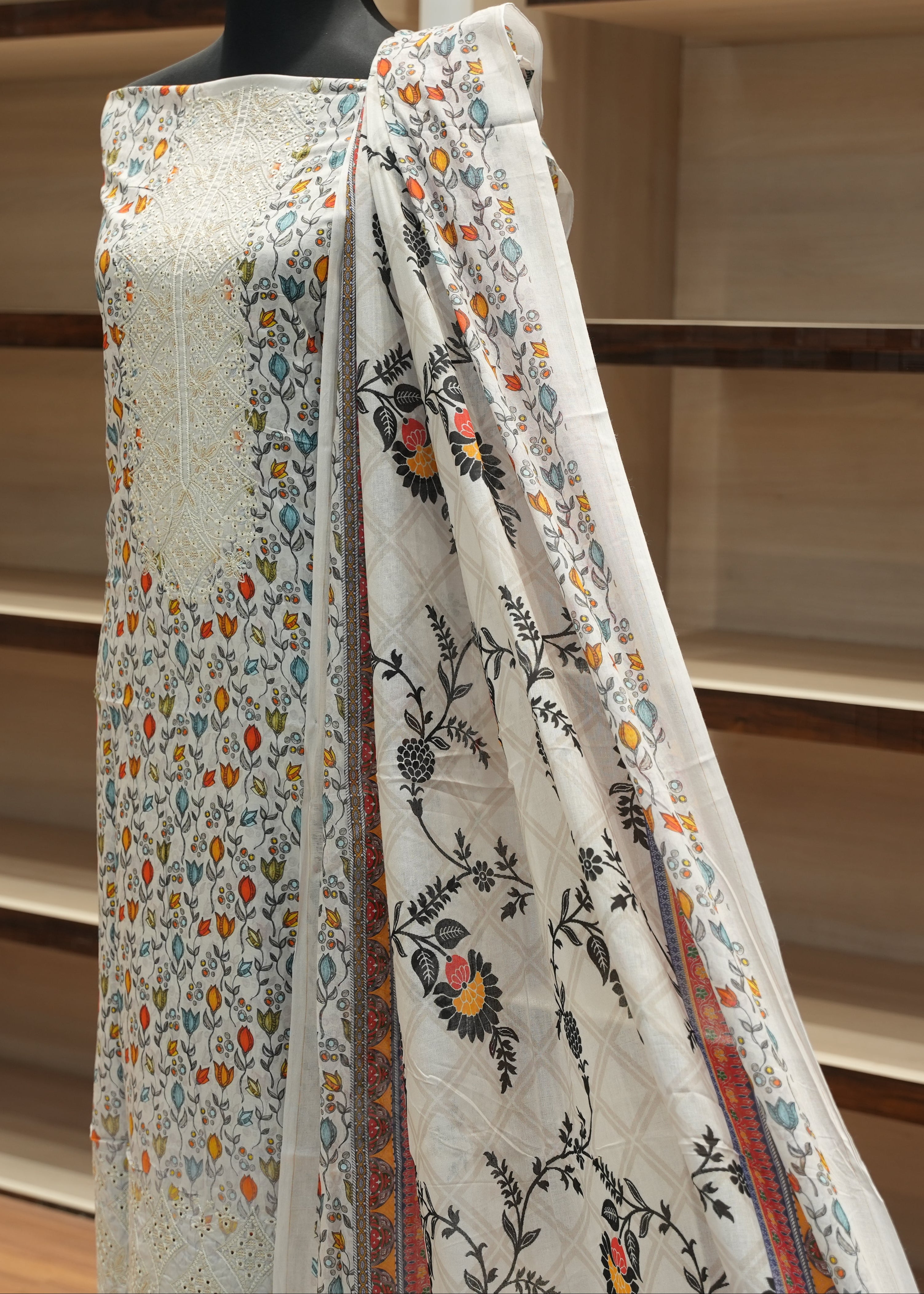 Floral patterned fabric draped over a mannequin against a wooden shelf background