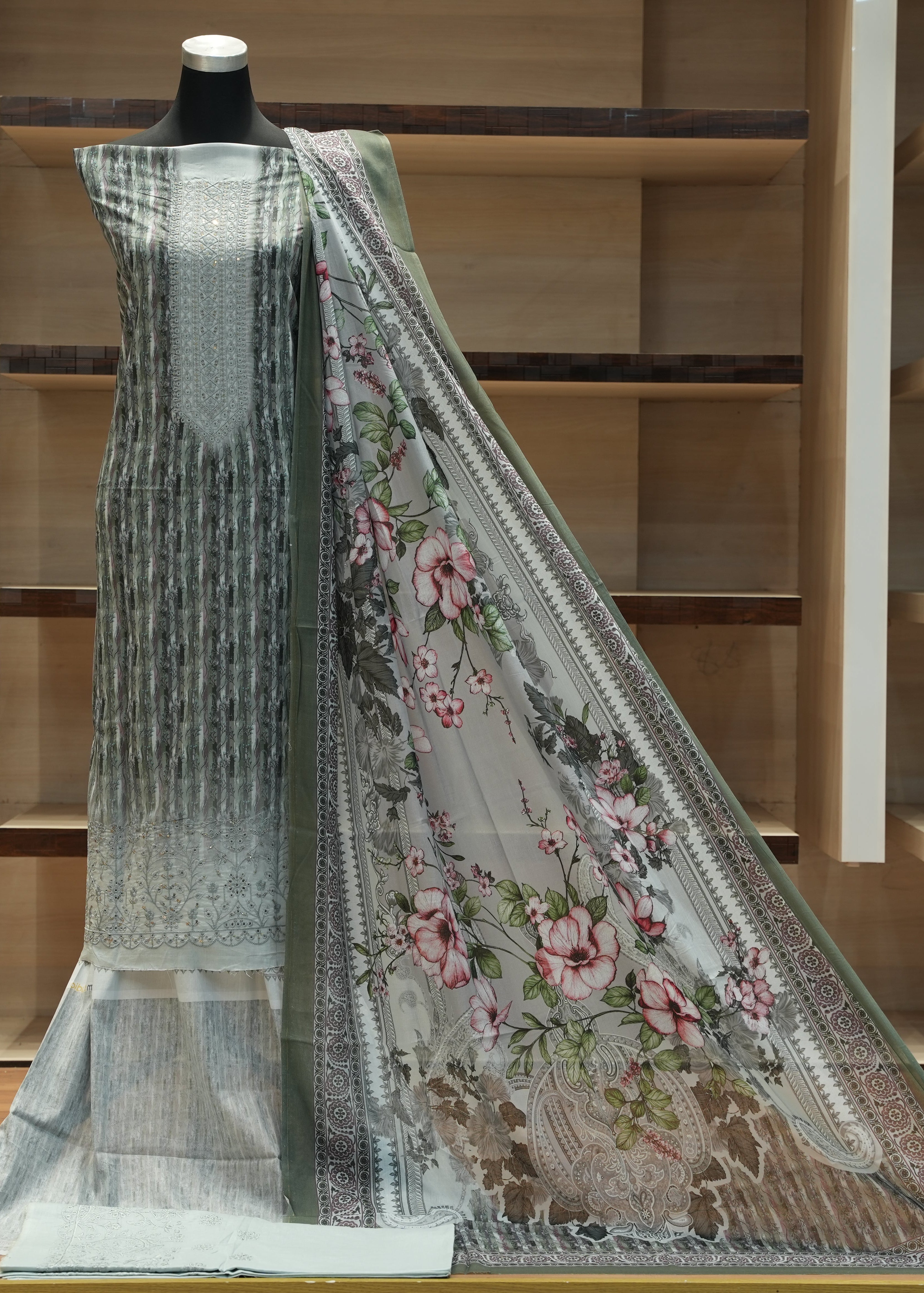 Embroidered fabric on a mannequin against a wooden shelf background