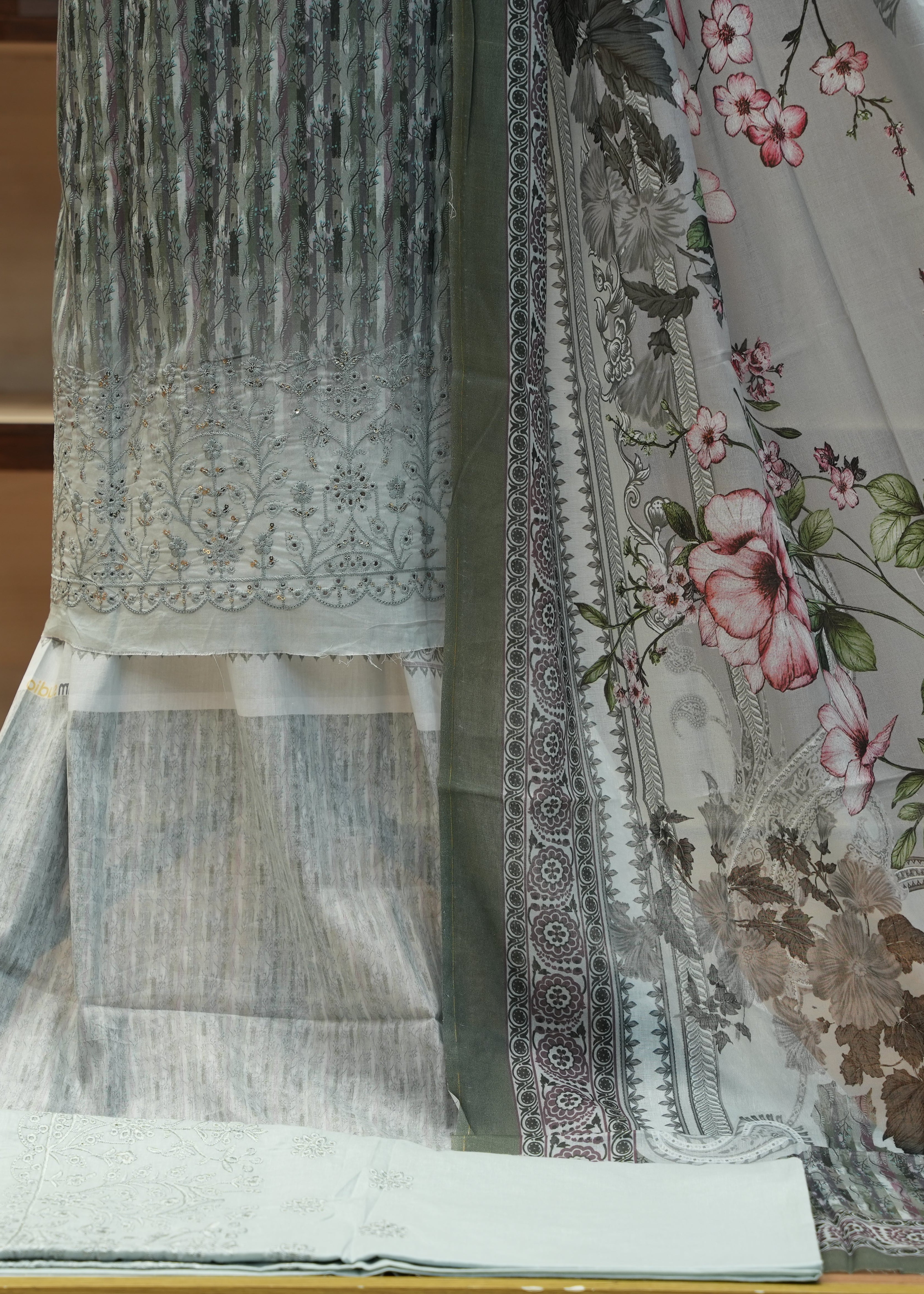 Two pieces of fabric, one with floral pattern and the other with intricate design, on a wooden surface.