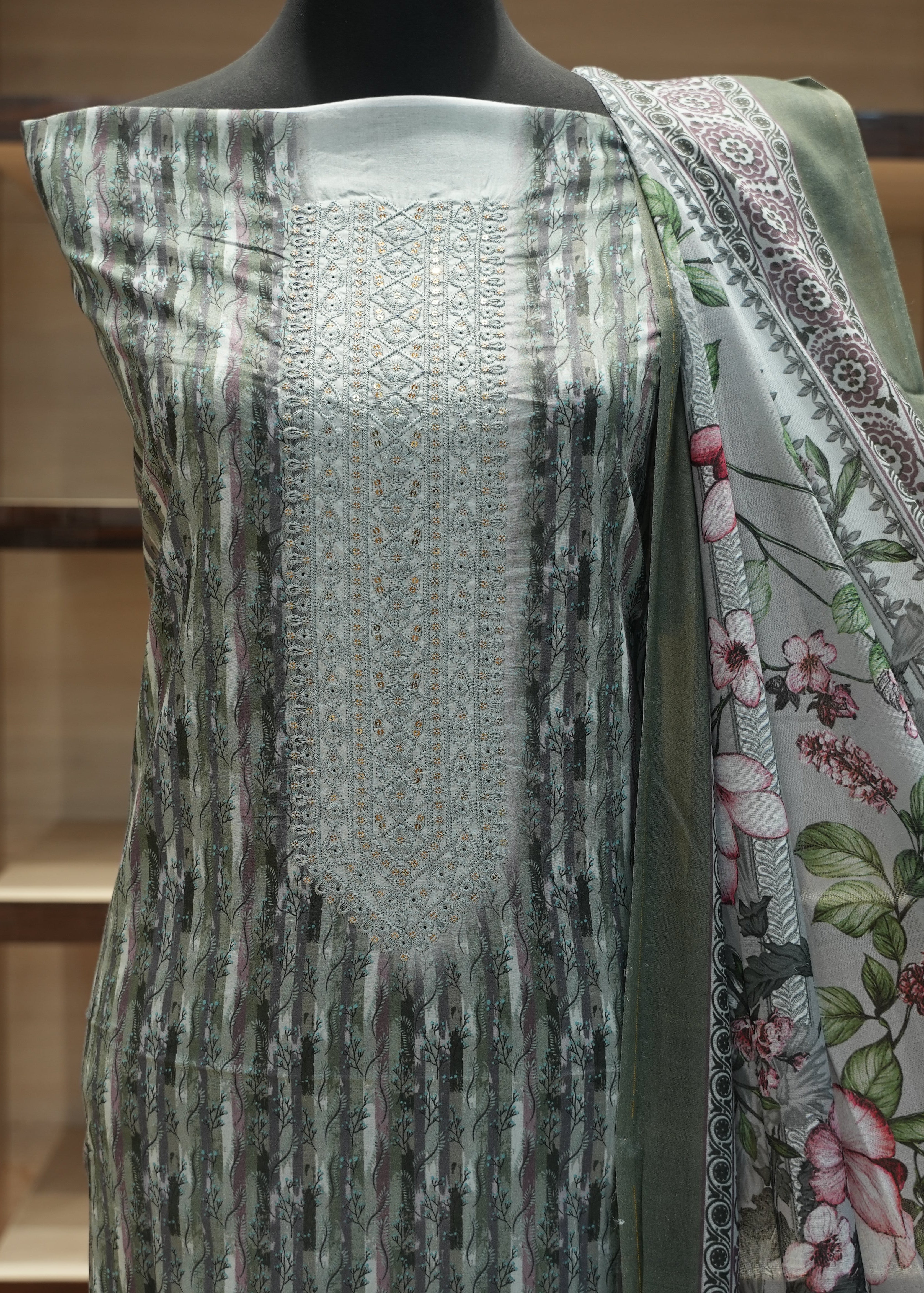 Mannequin wearing a patterned dress with a floral shawl in a store setting
