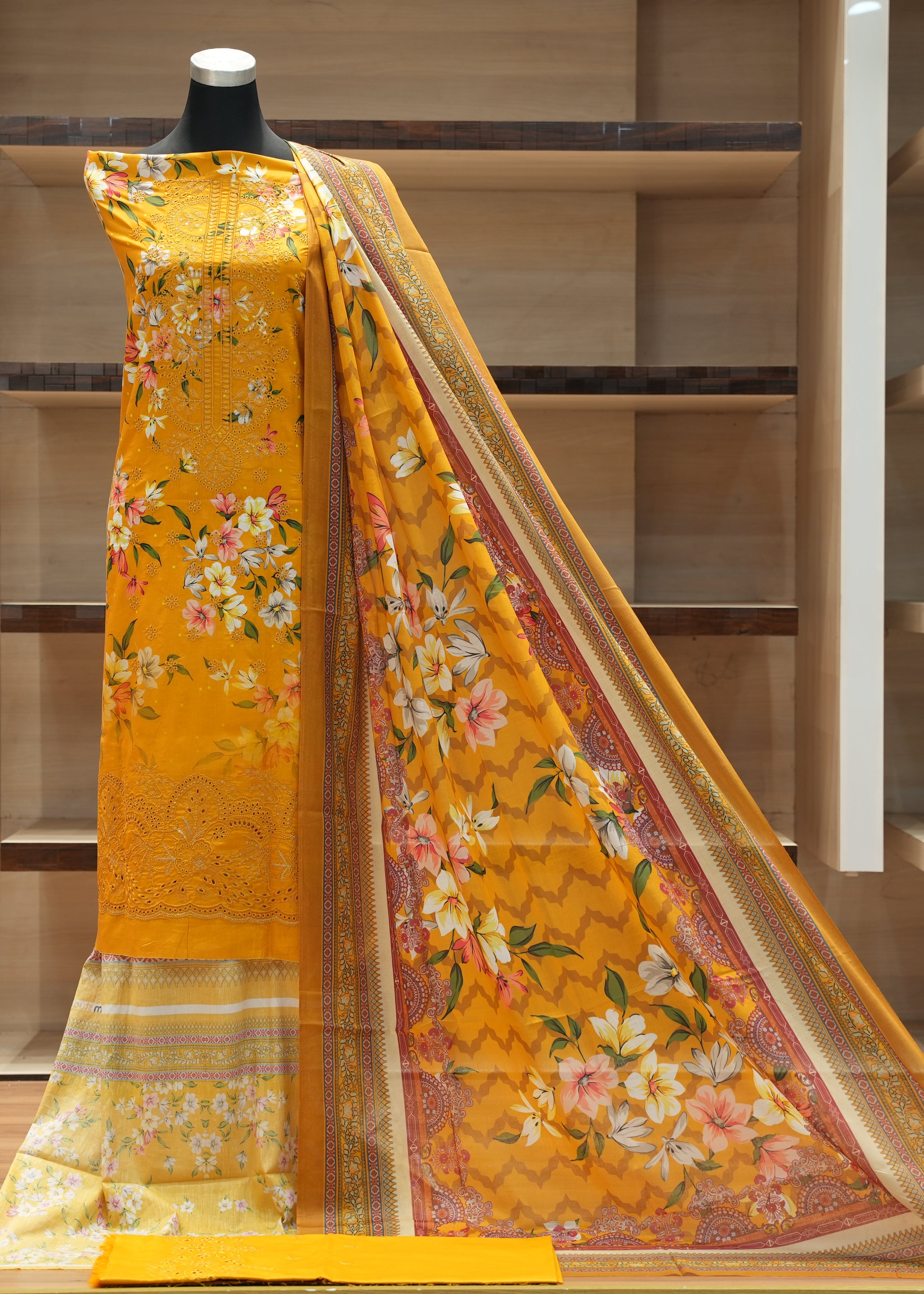 Yellow floral saree with a mannequin against a wooden background