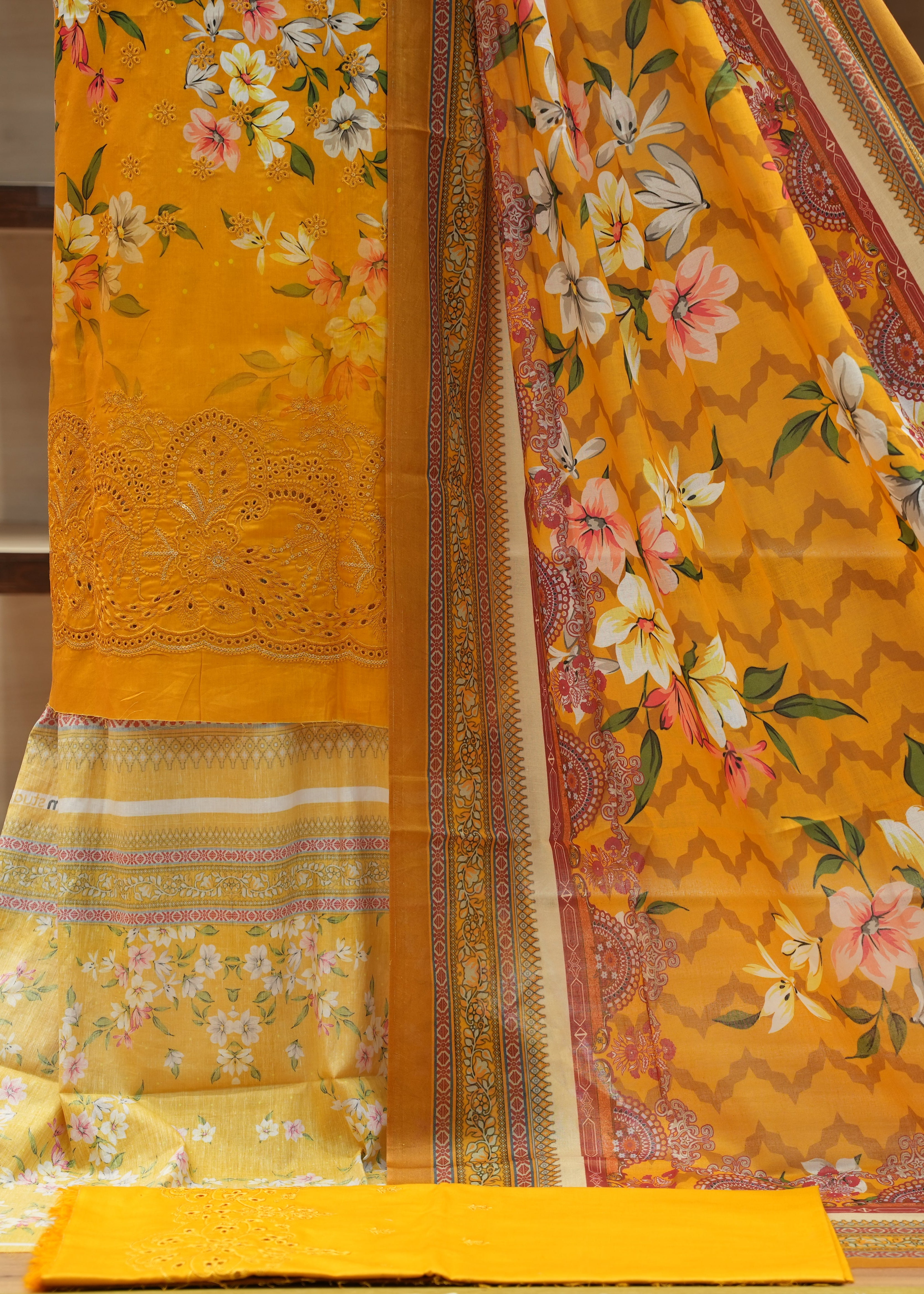 Yellow floral saree with intricate patterns on a wooden surface