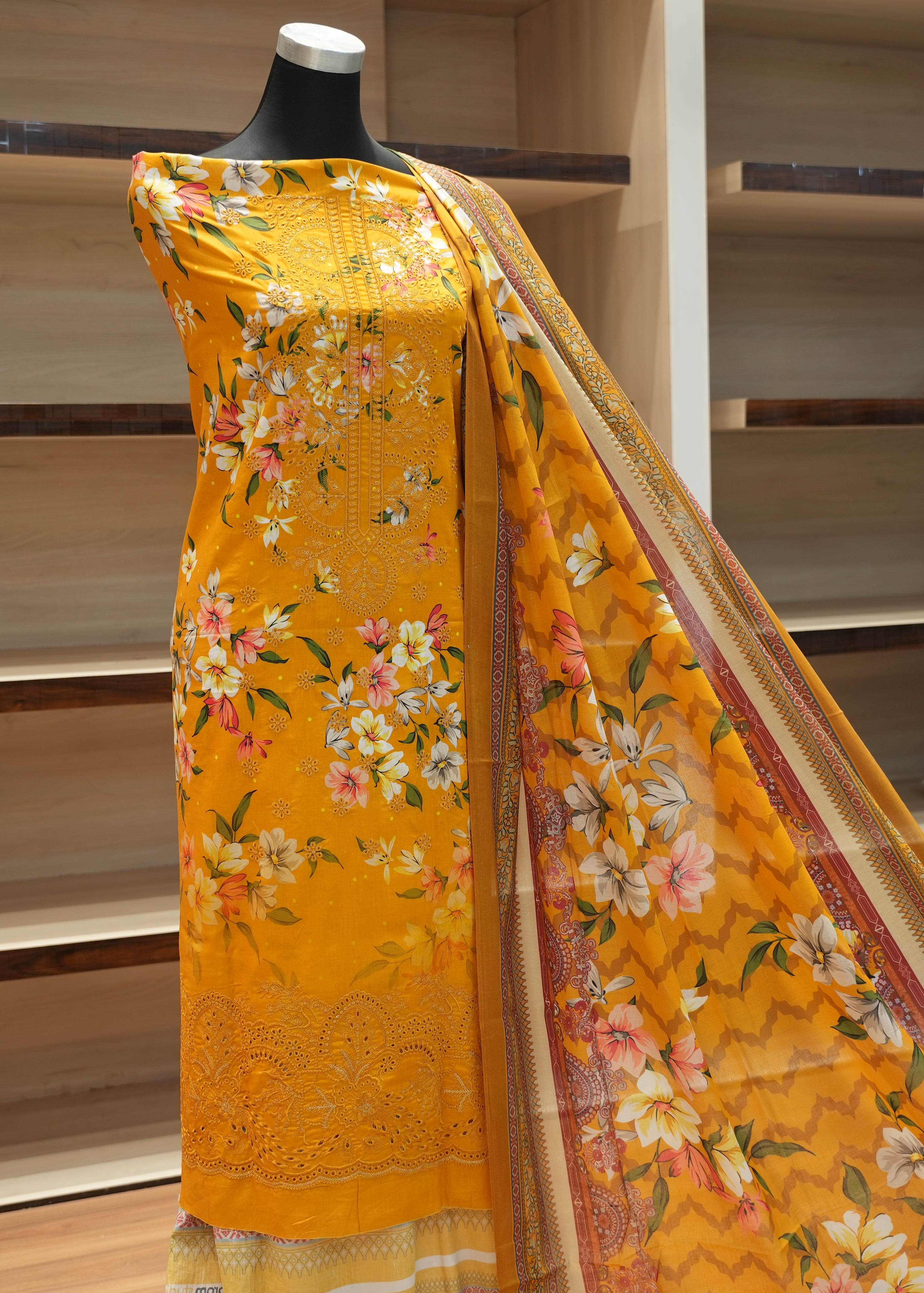 Yellow floral saree on a mannequin against a wooden shelf background