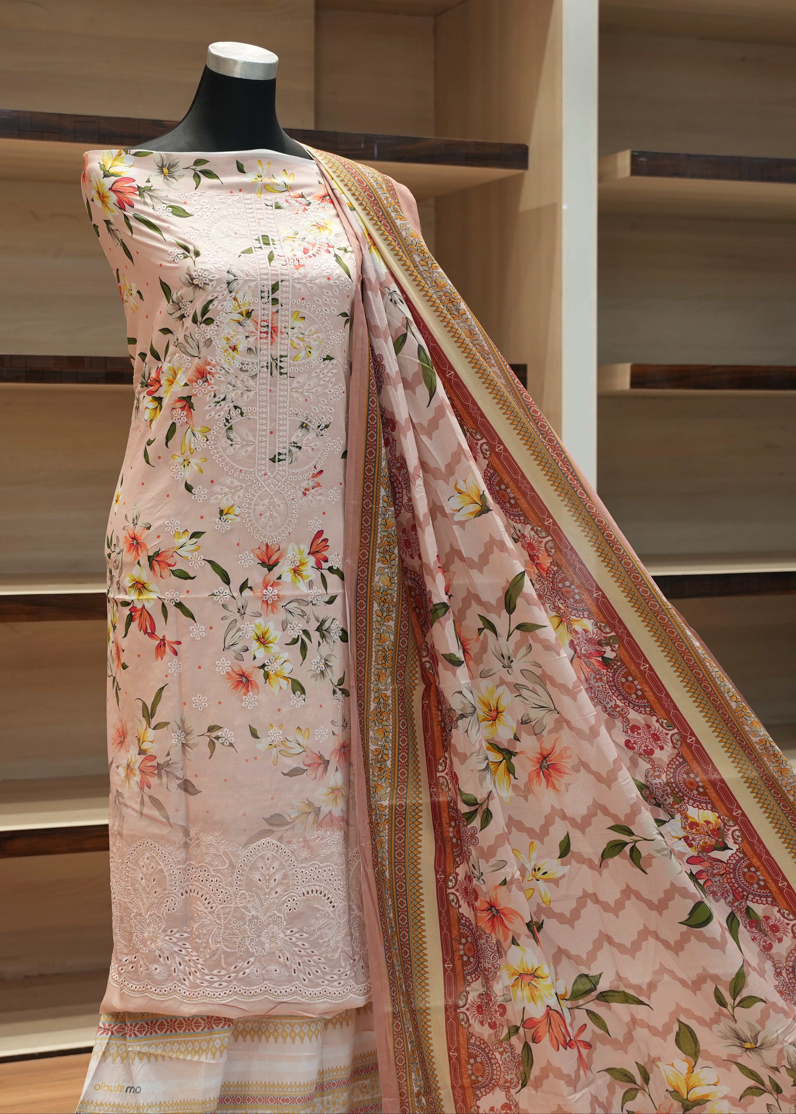 Floral saree on a mannequin against a wooden shelf background