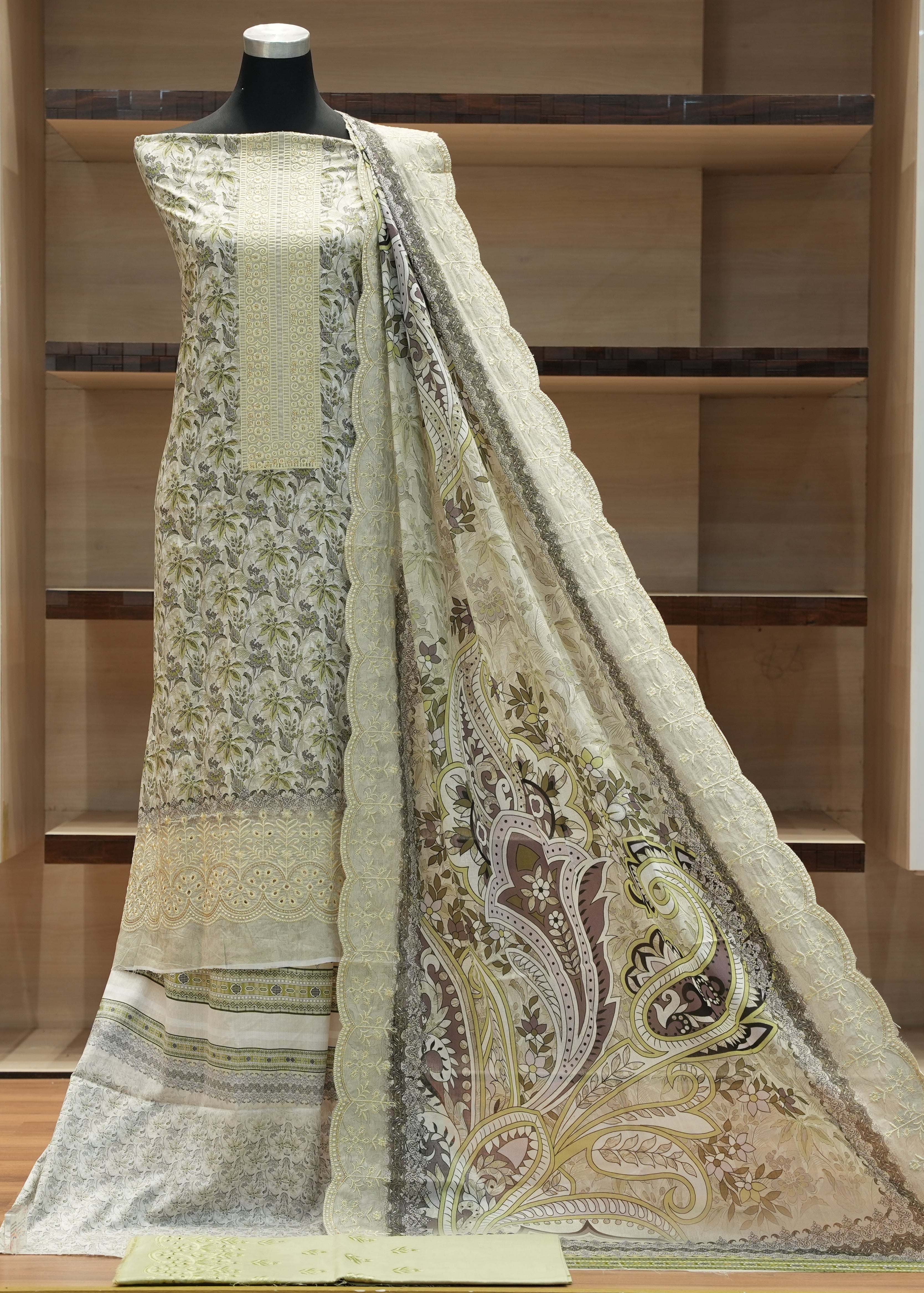 Traditional outfit with embroidered fabric on a mannequin against a wooden shelf background