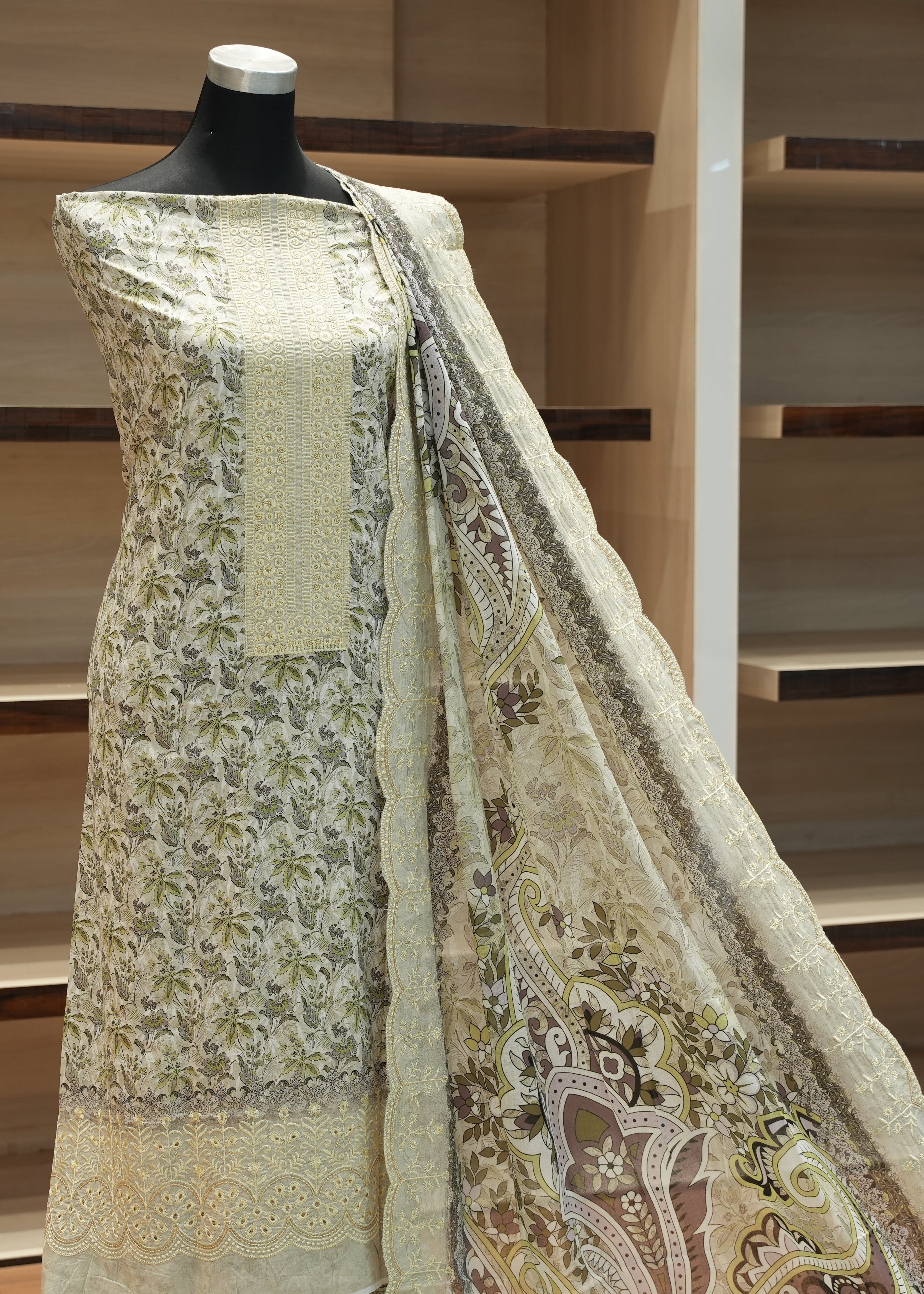 Mannequin wearing a traditional outfit with a floral pattern against a wooden shelf background
