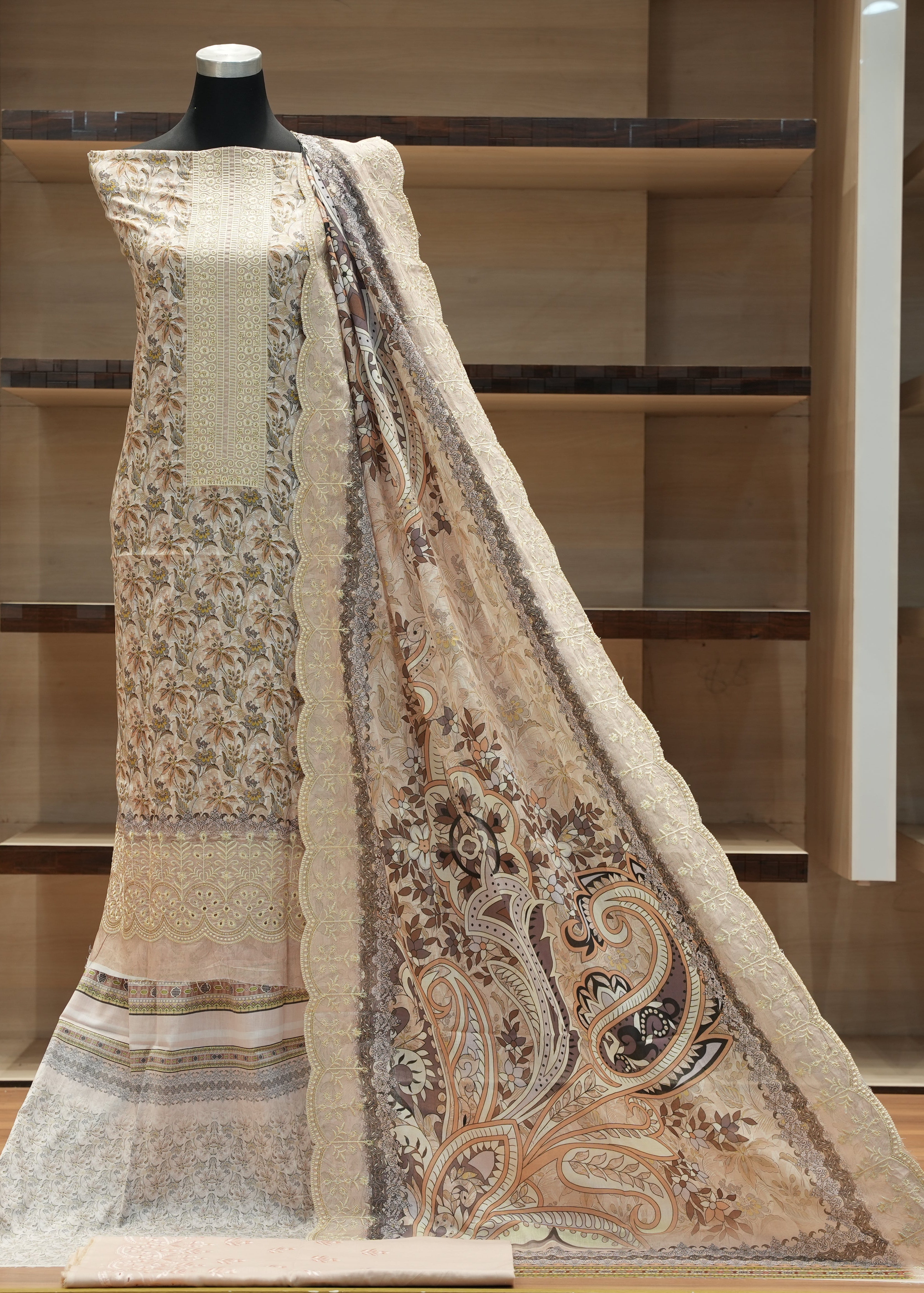 Mannequin wearing a traditional outfit with a floral patterned dupatta against a wooden background