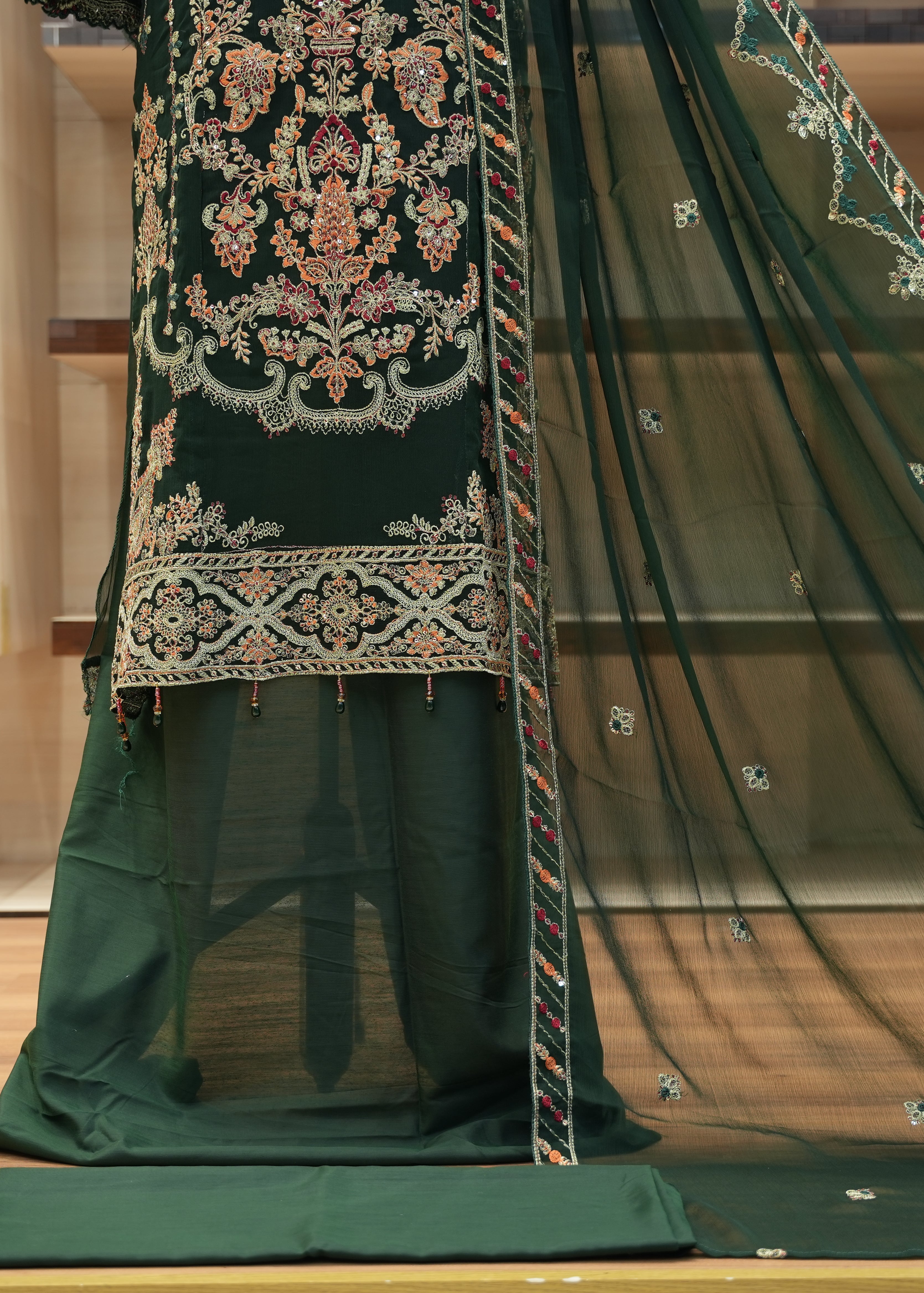 Green embroidered traditional outfit on a wooden floor