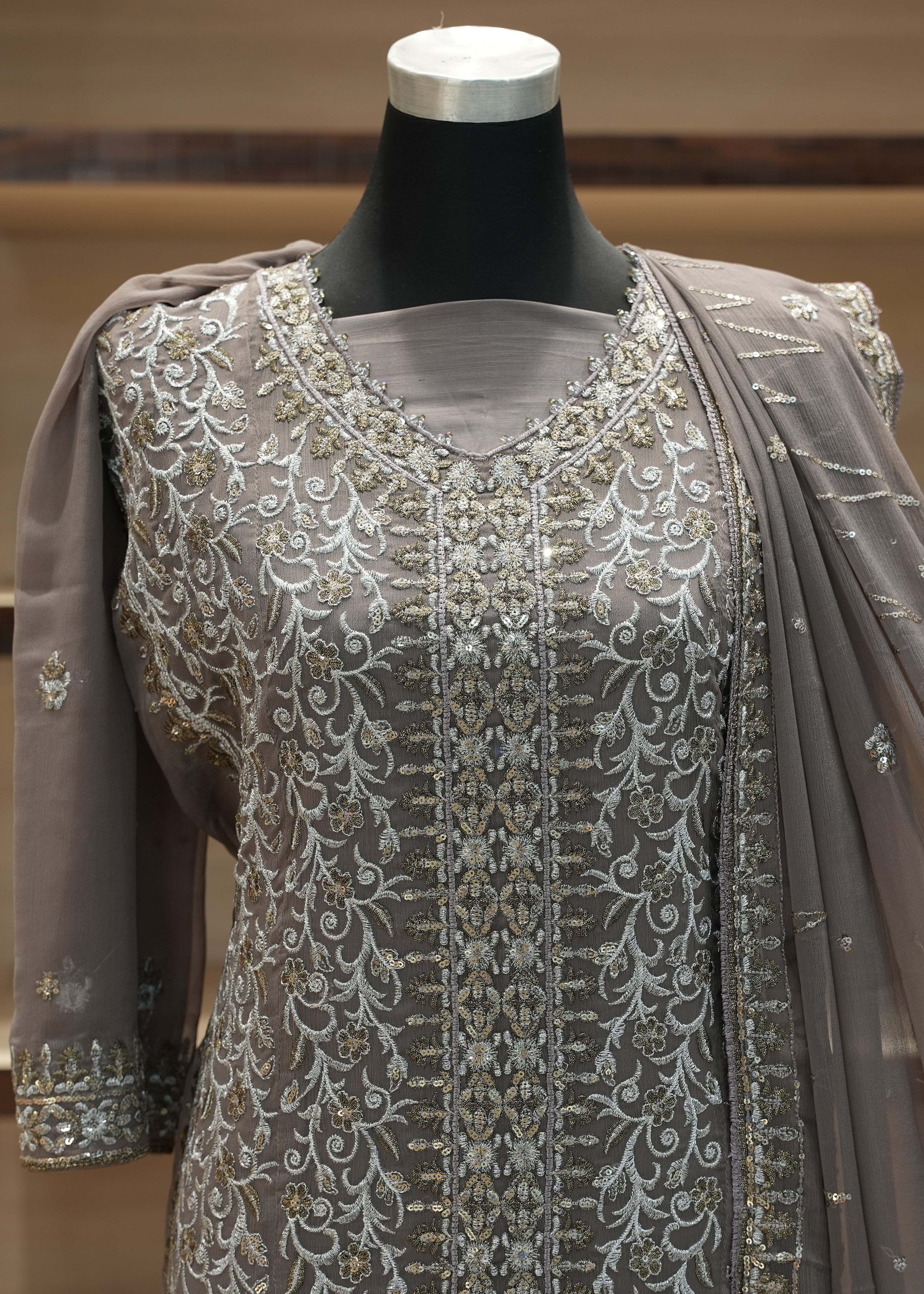 Gray embroidered outfit on a mannequin against a wooden background