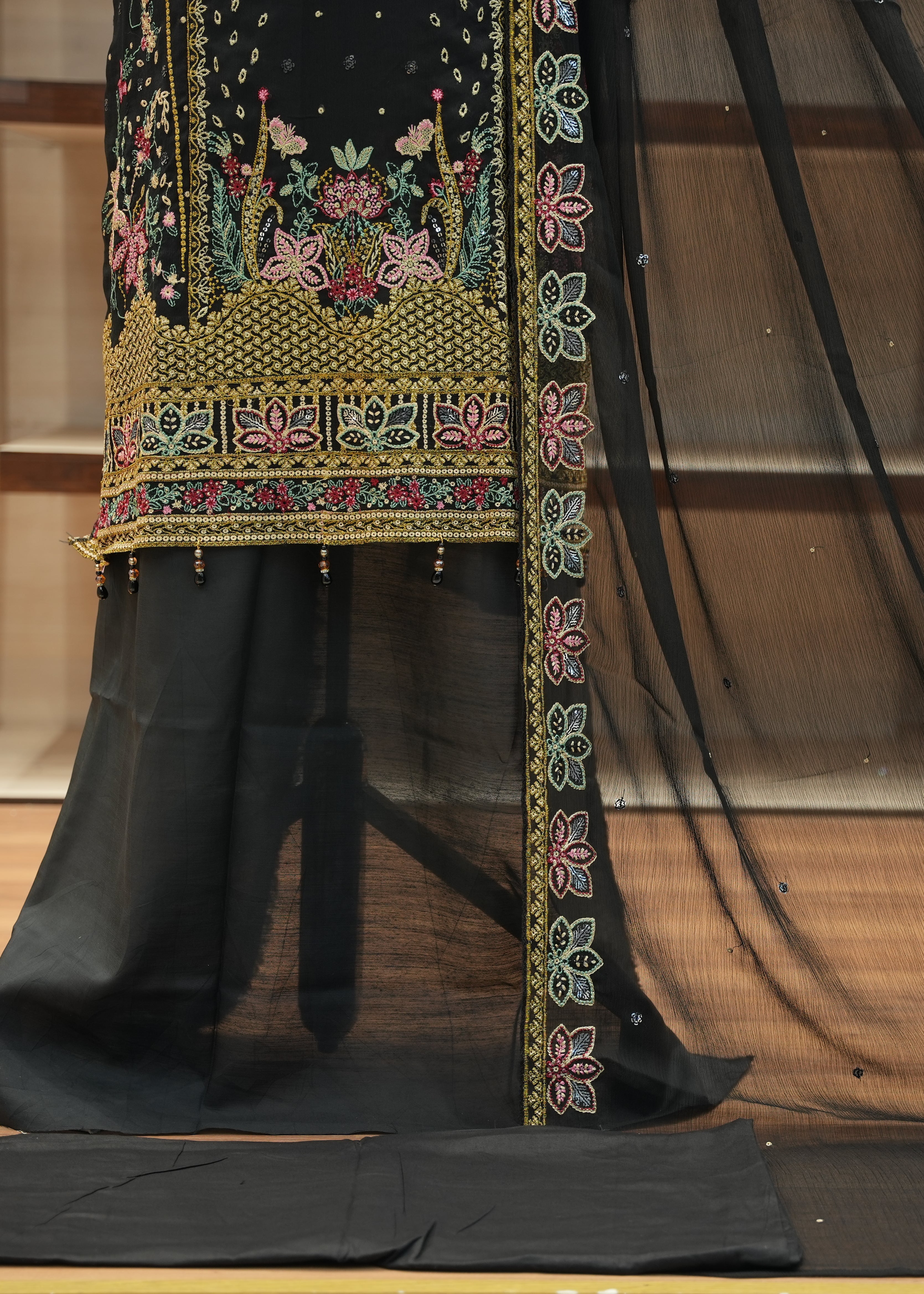 Black embroidered fabric with colorful patterns on a wooden floor