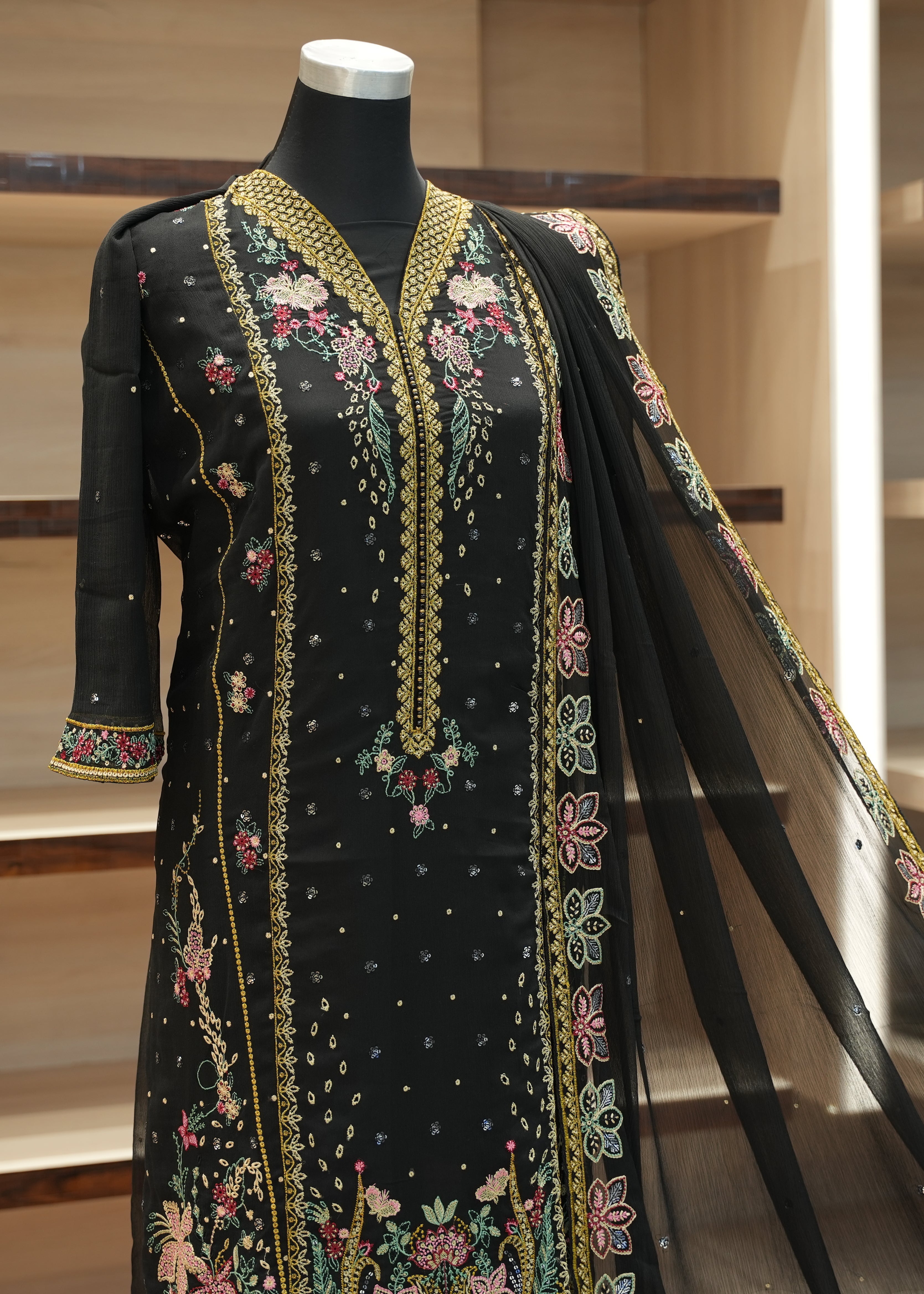 Black embroidered dress on a mannequin against a neutral background