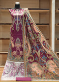 Mannequin wearing a traditional outfit with a large patterned fabric draped over it against a wooden background.