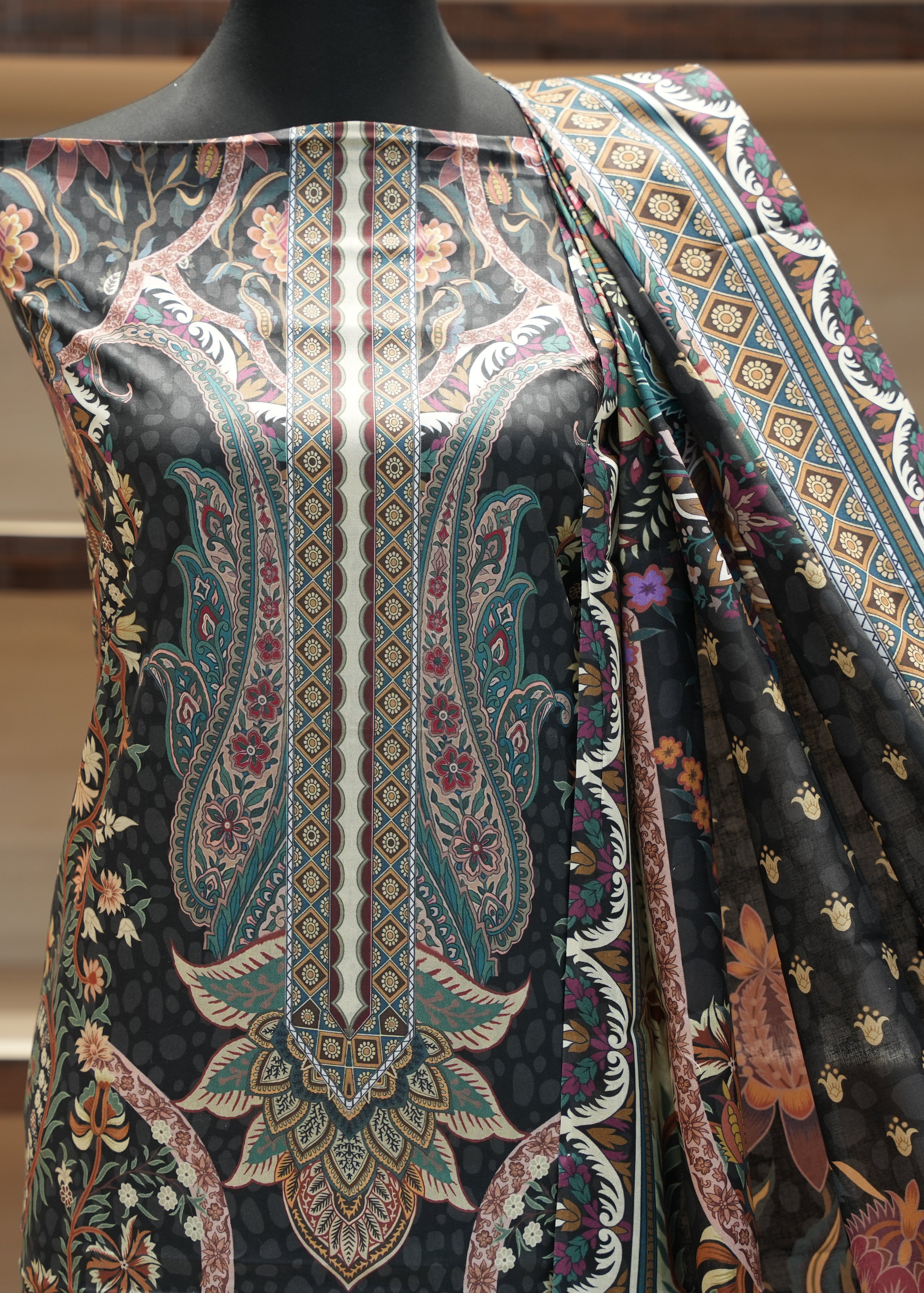 Mannequin wearing a black fabric with intricate paisley patterns in various colors.
