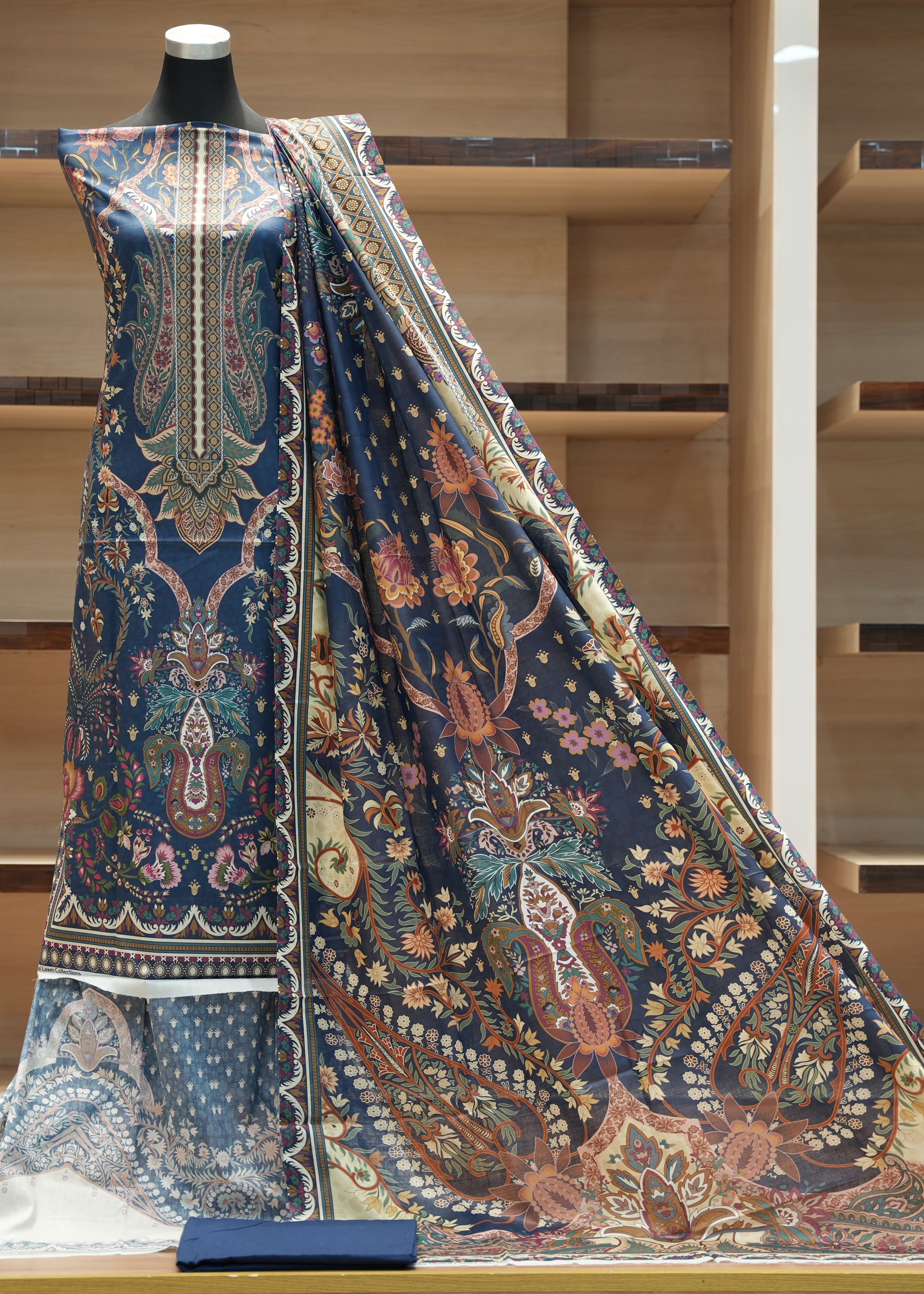 Mannequin wearing a large piece of patterned fabric with a wooden shelf background