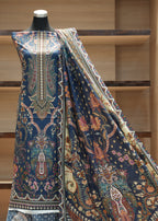 Mannequin wearing a piece of patterned fabric with a decorative design in a neutral setting.