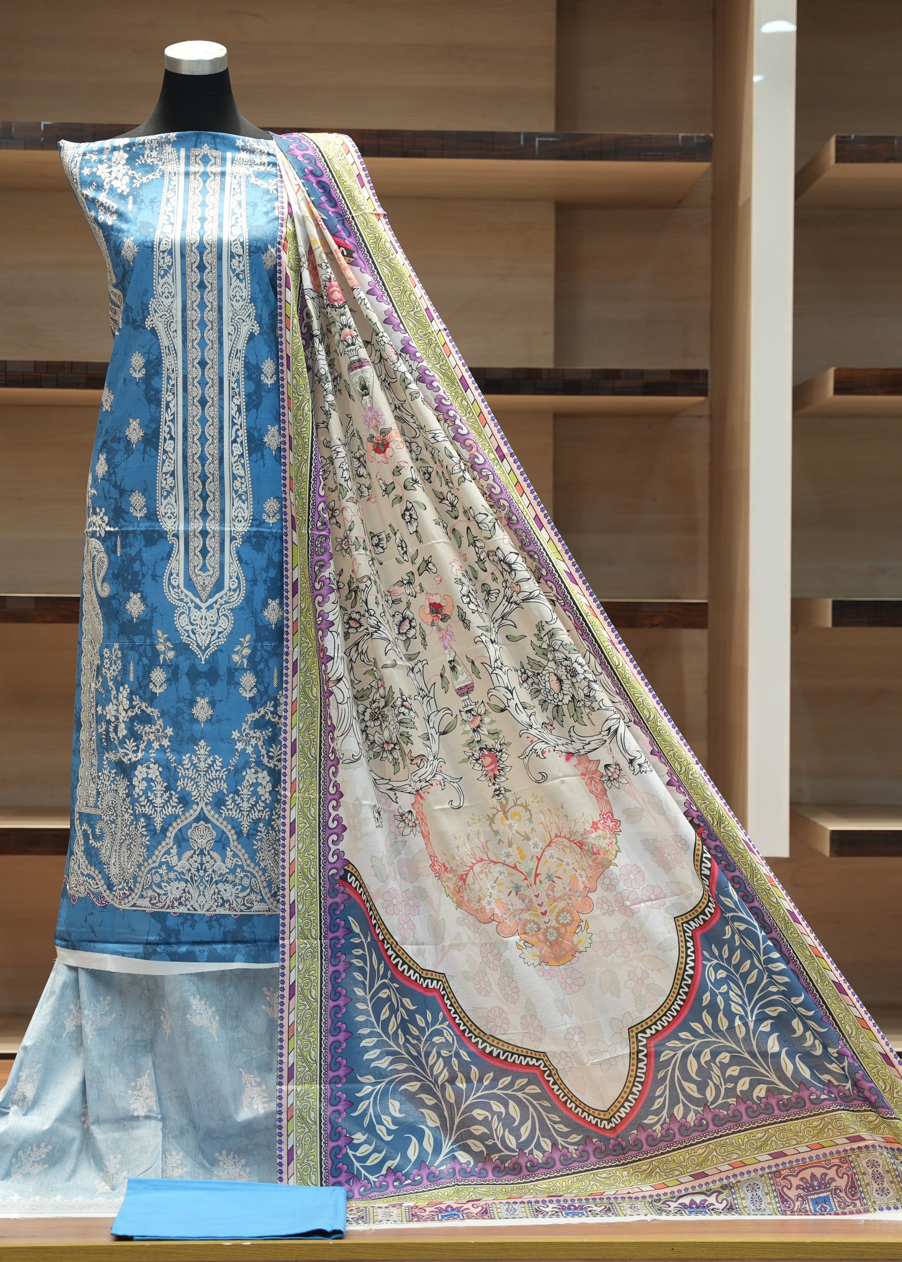 Traditional embroidered fabric on a mannequin with a wooden shelf background