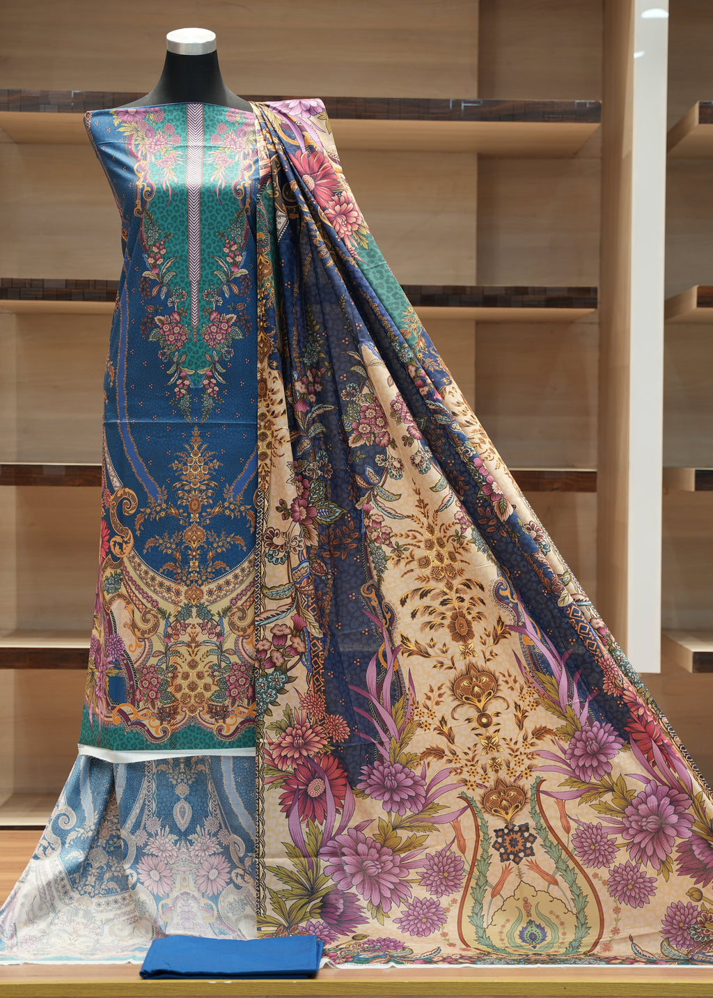 Colorful patterned fabric draped over a mannequin against a wooden shelf background
