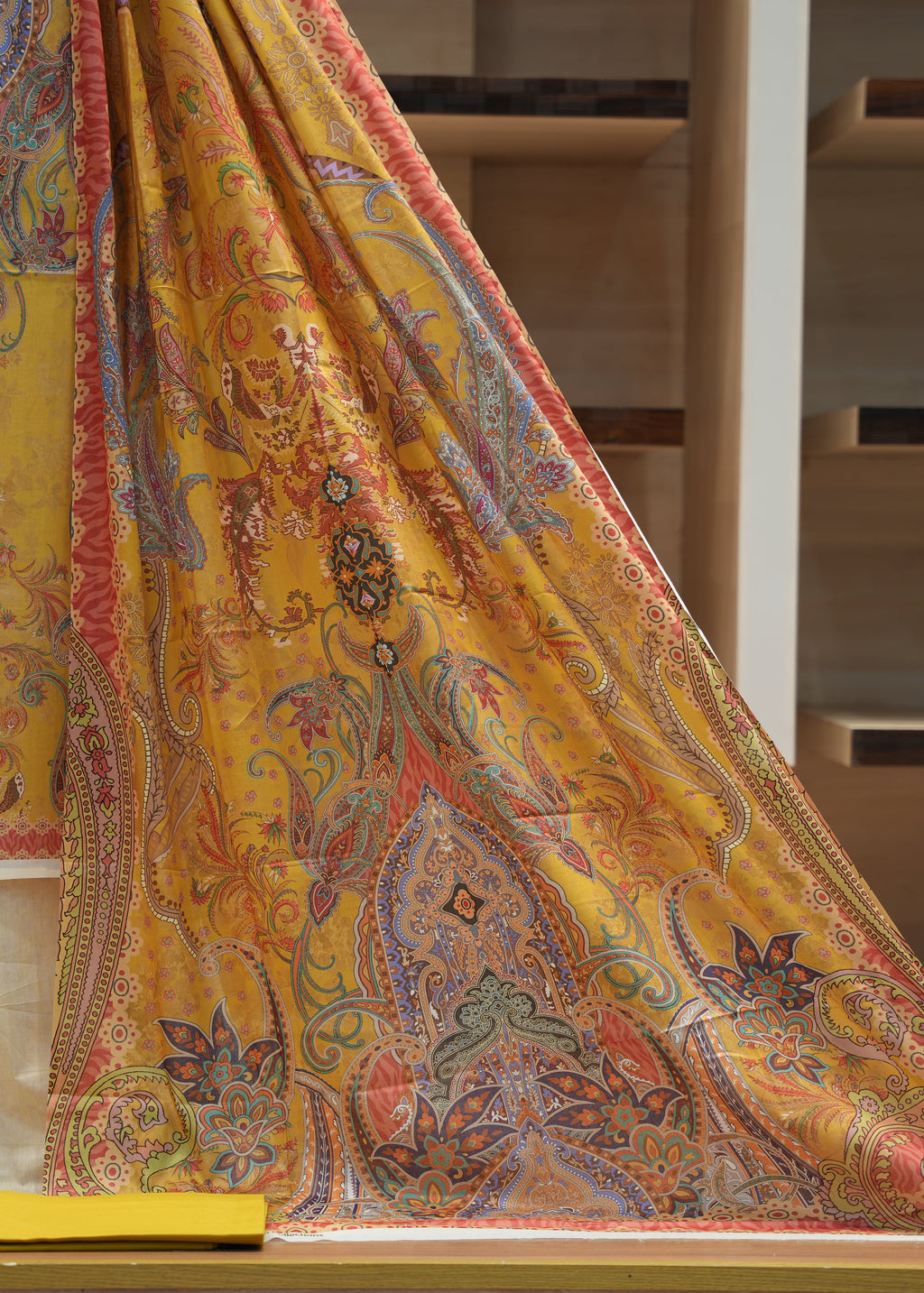Yellow embroidered fabric with intricate patterns on a wooden surface