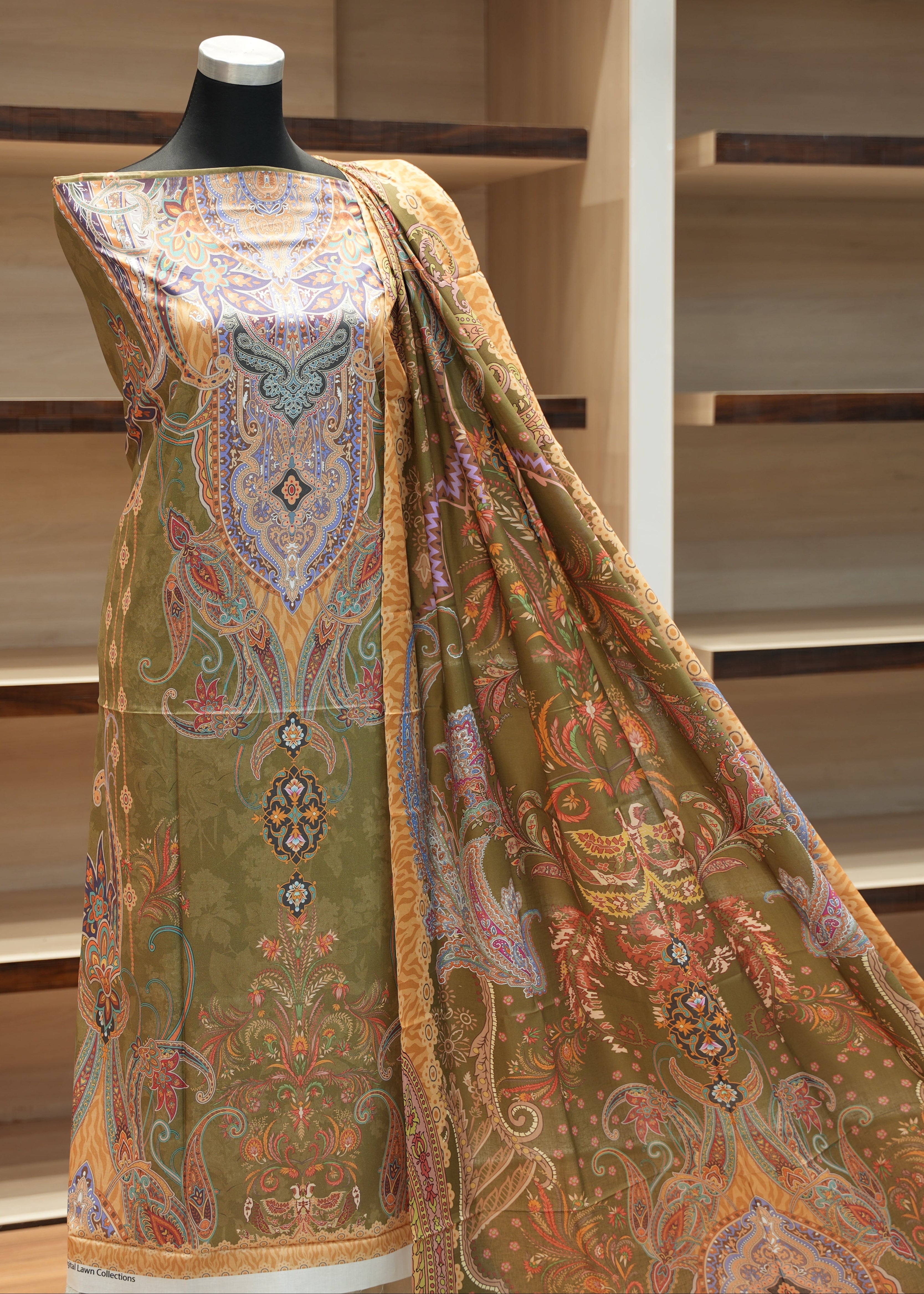 Mannequin wearing a traditional embroidered garment with a patterned design against a wooden background.