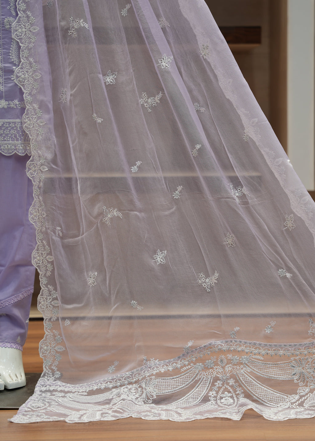 White embroidered lace fabric on a wooden surface with a blurred background
