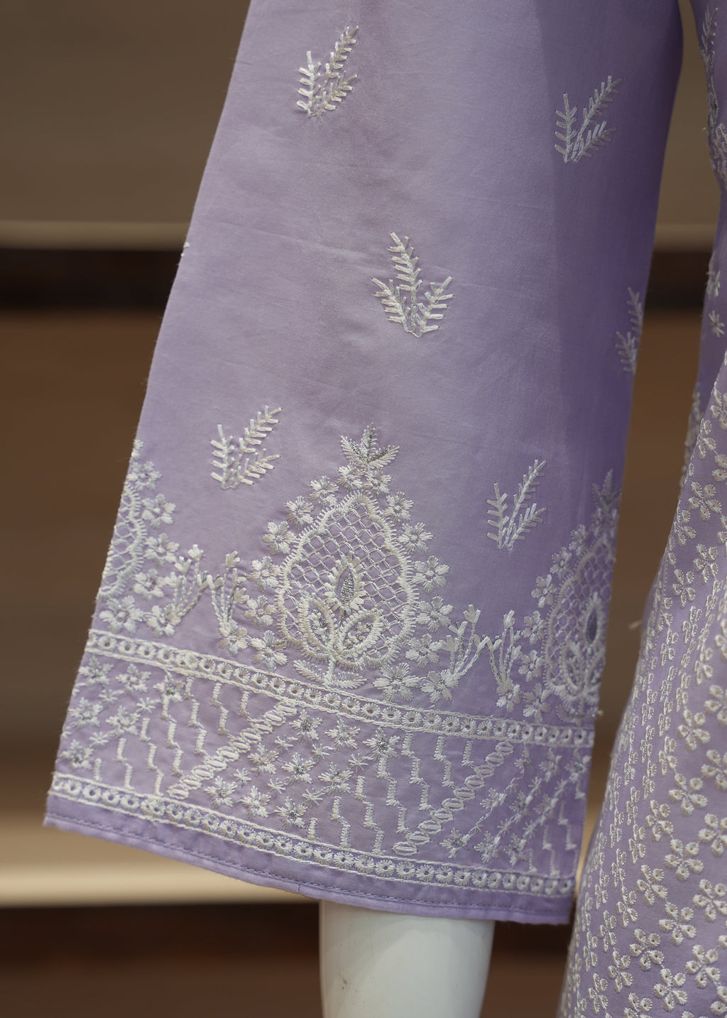 Purple fabric with white embroidery on a mannequin against a neutral background